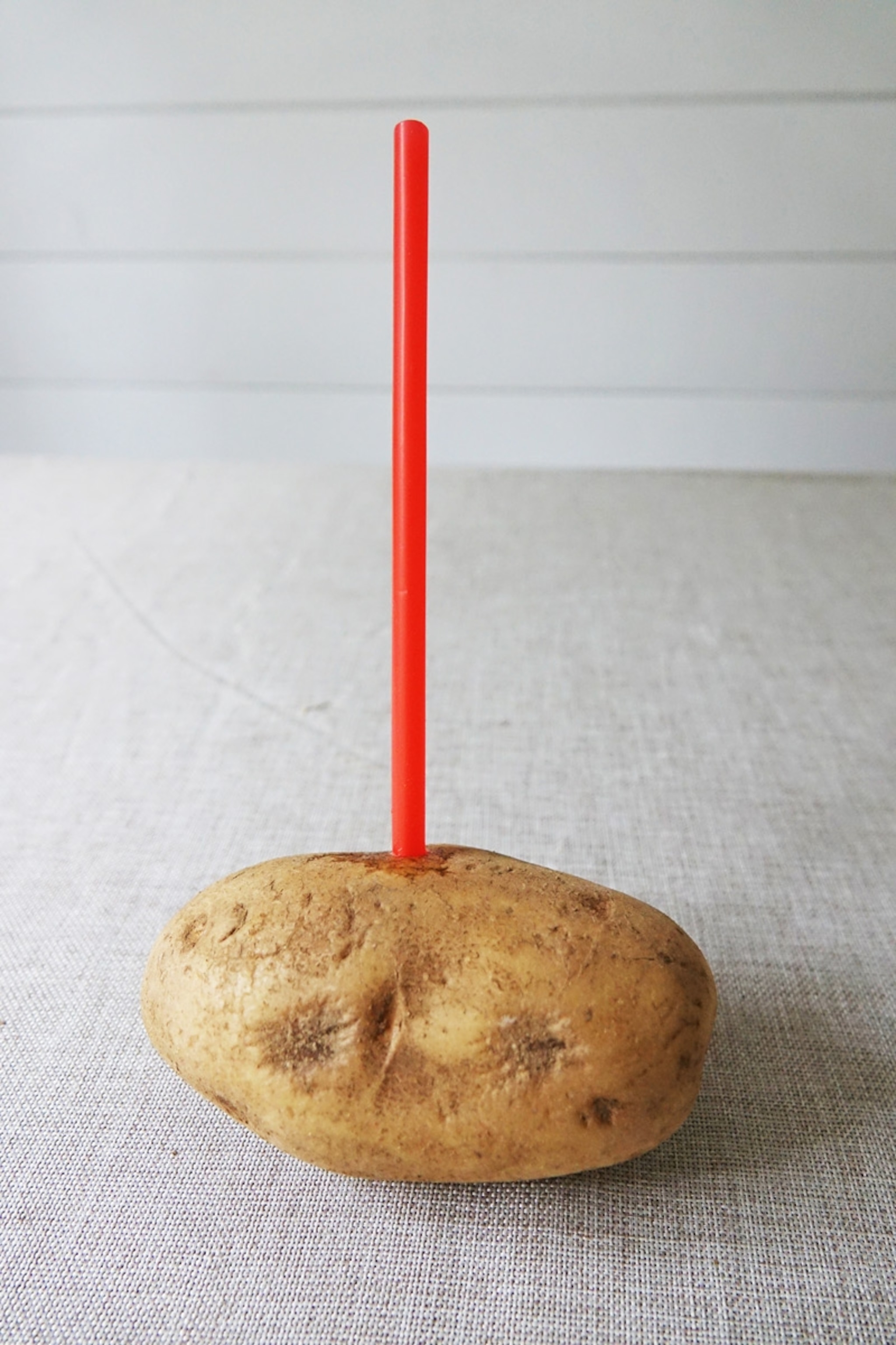 A potato with a red straw stuck in the top.