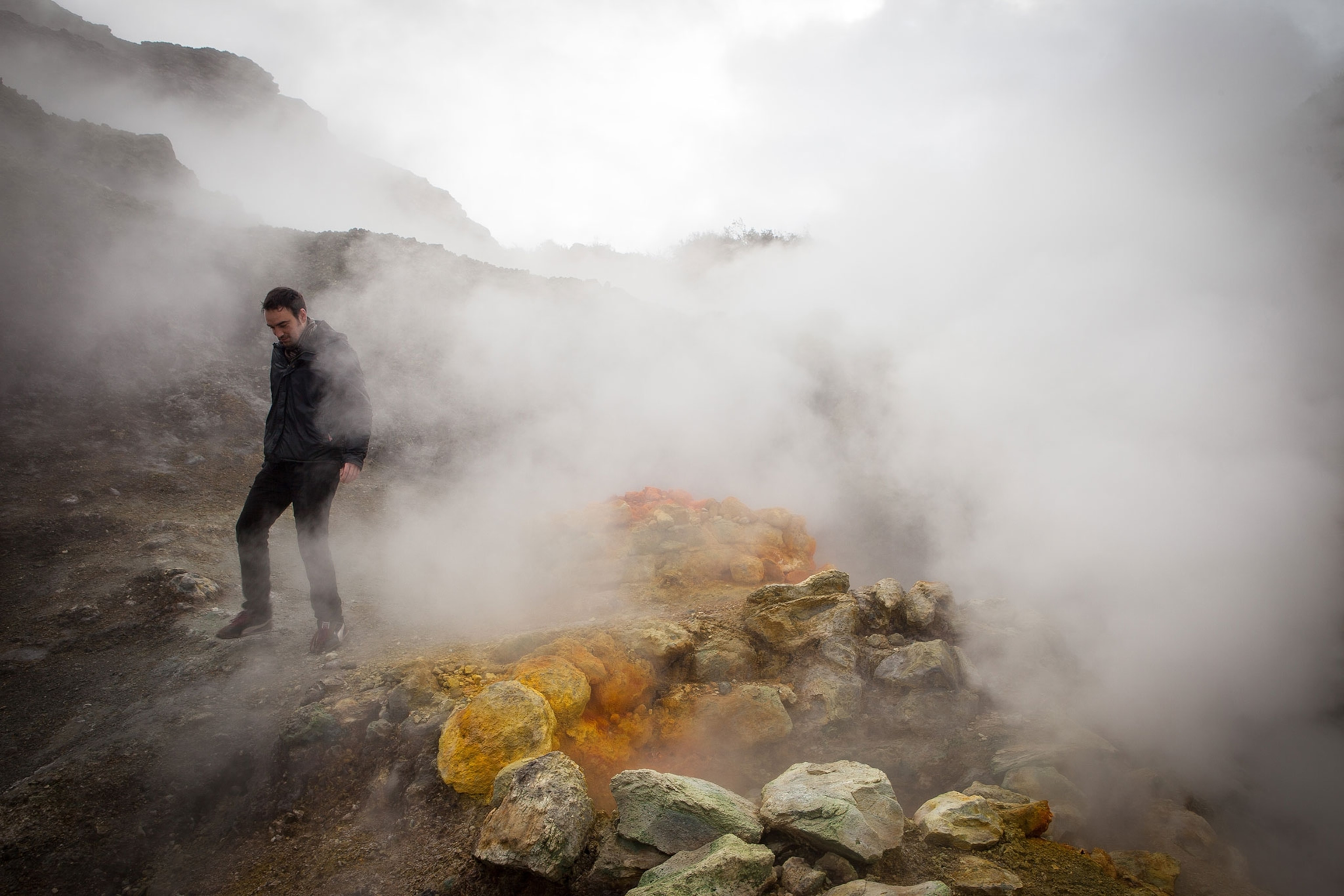 a man walking through highly active volcanic fields in italy