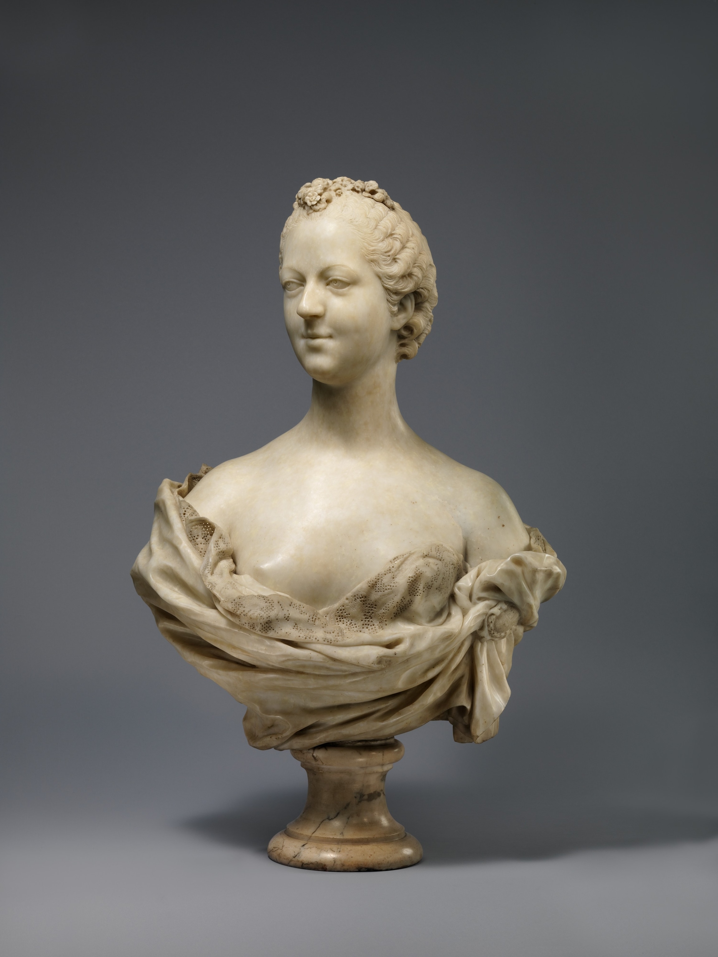 A bust figure cared in off white on a gray background.