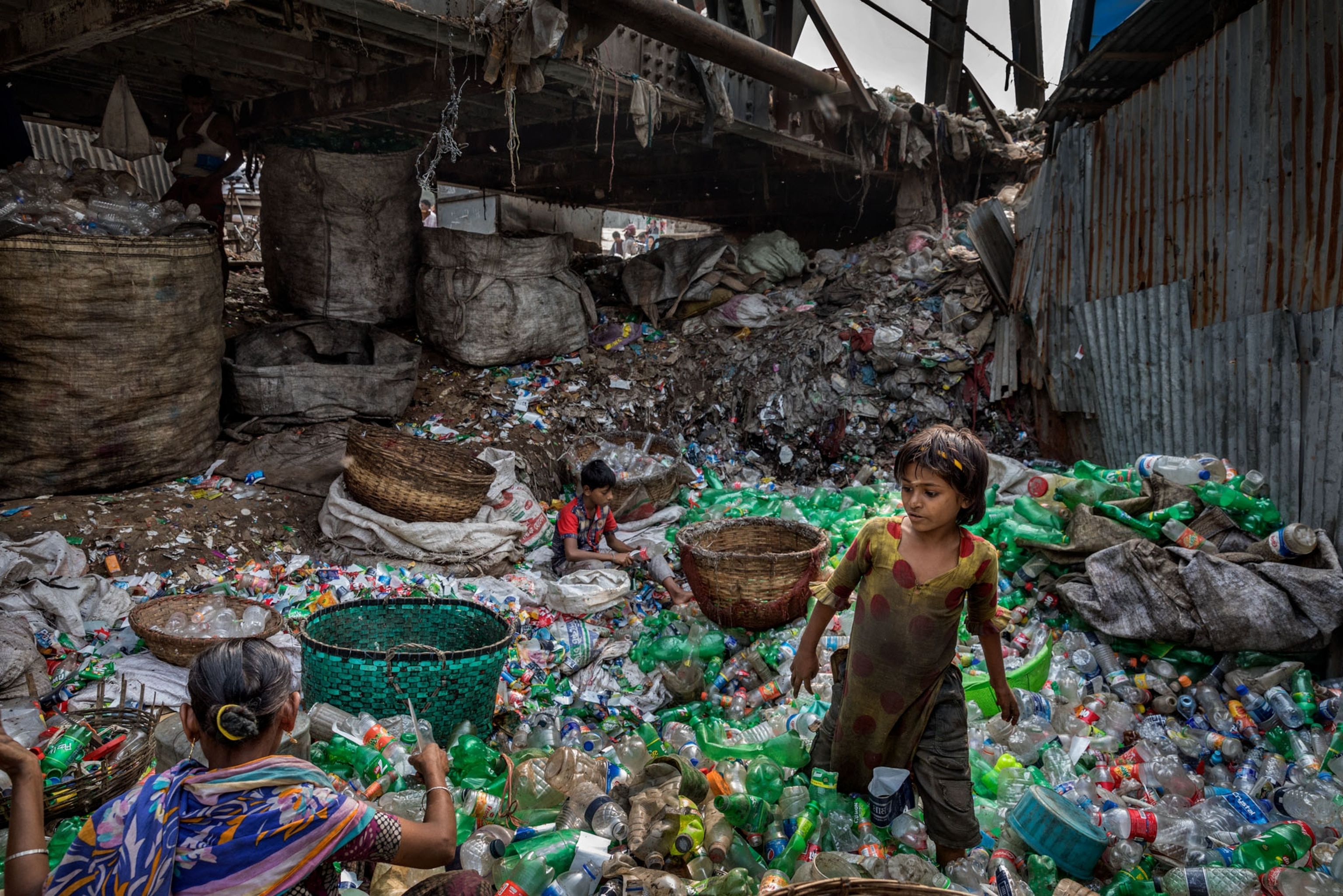 a family removing labels from plastic bottles under a bridge
