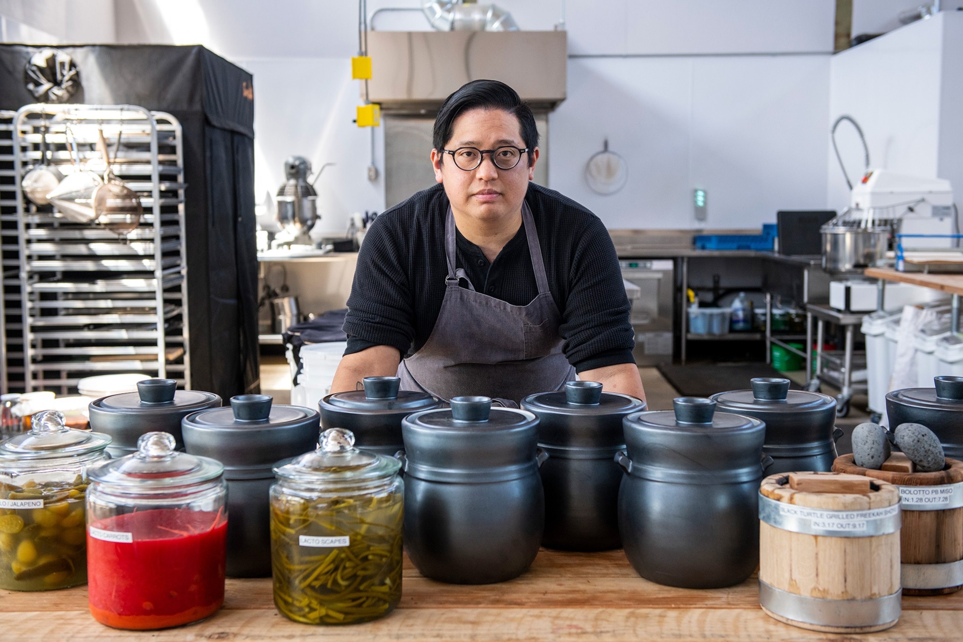 ōkta Larder Chef Larry Nguyen at the Larder Lab surrounded by jars.
