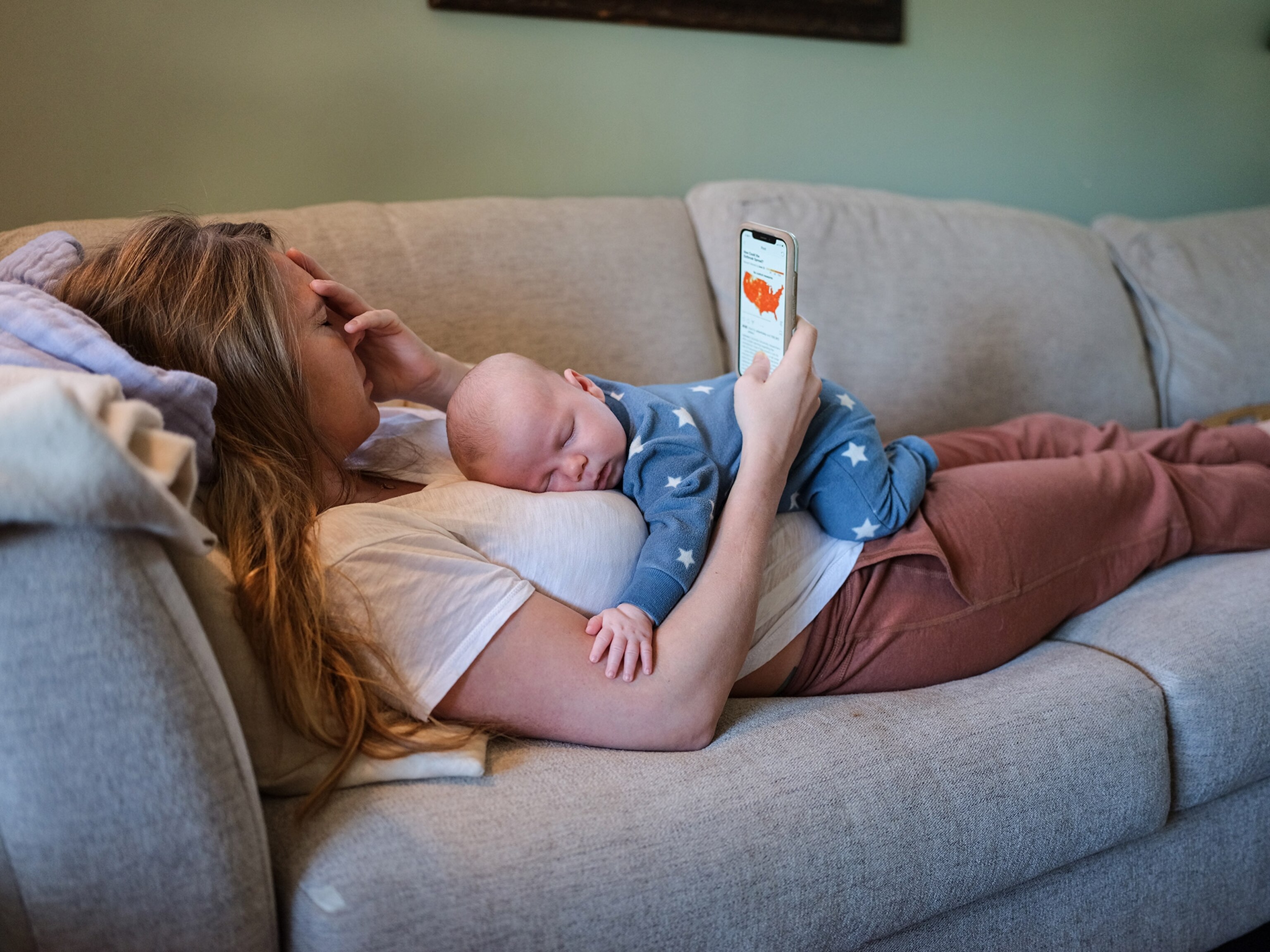 a woman laying on a couch with her baby on her chest