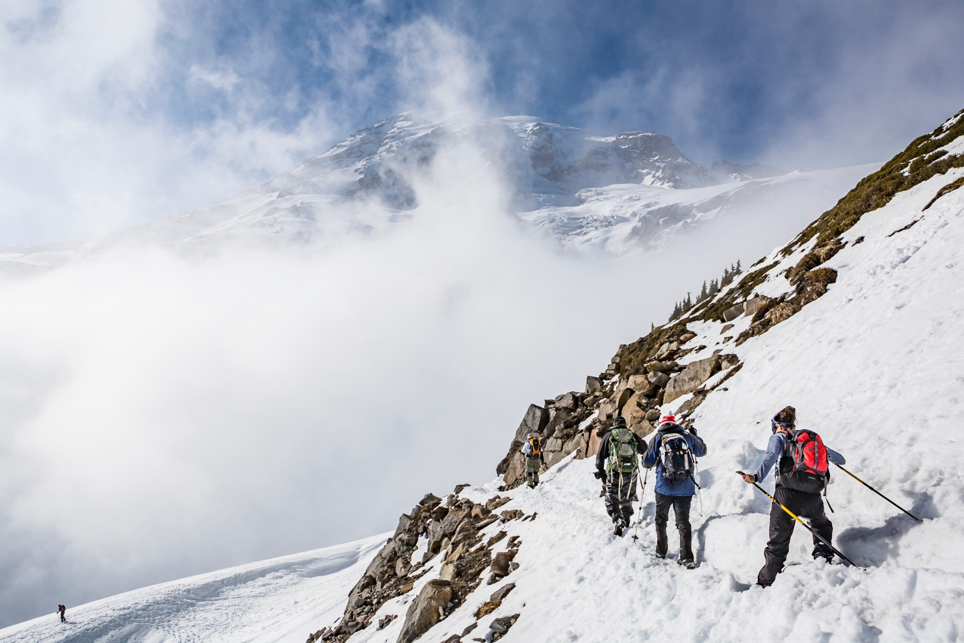 climbers along a snowy and cloudy mountainside in Mount Rainier National Park