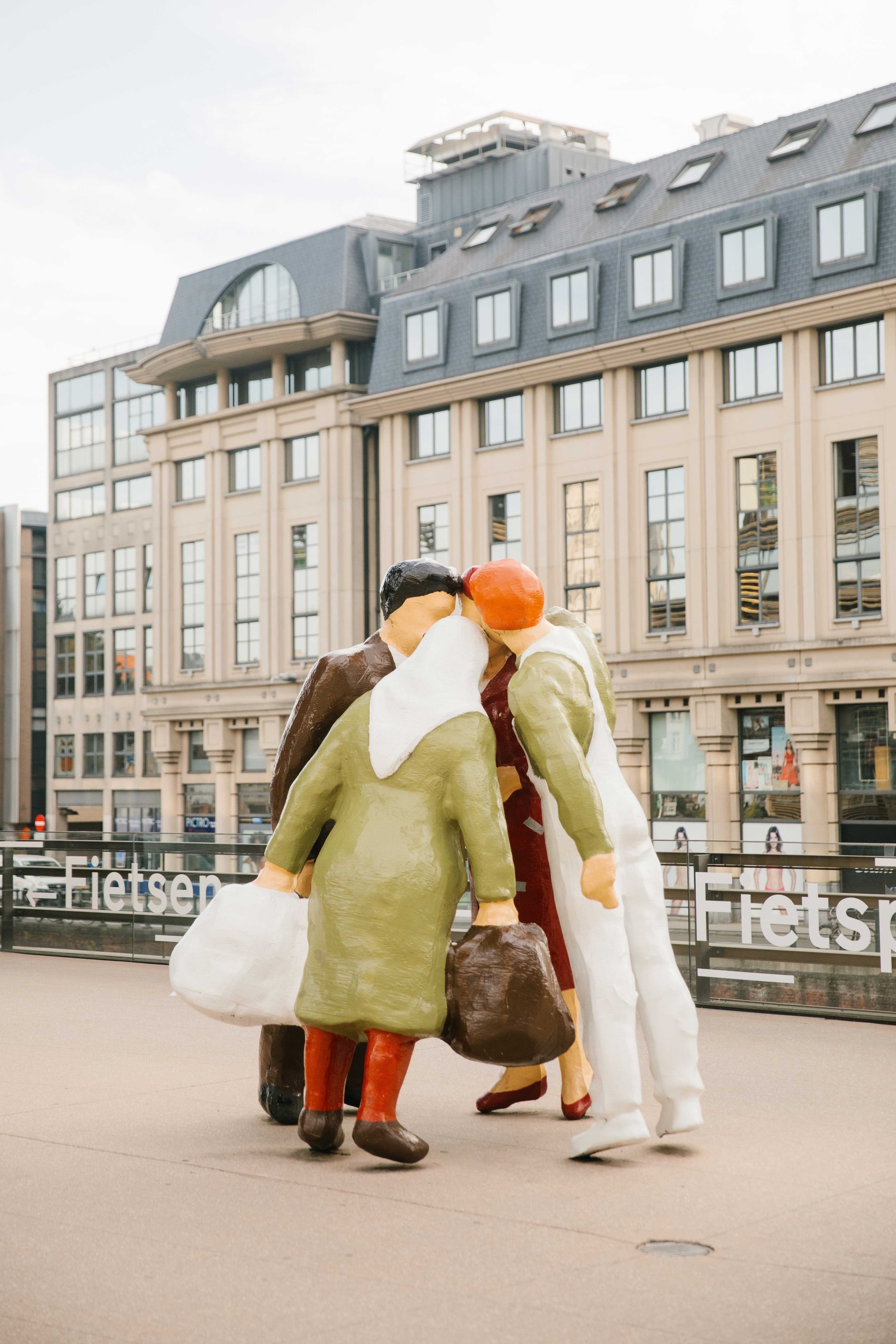 Street sculpture by Belgian artist Michaël Borreman, who lives and works in Ghent. It shows four faceless people huddled together, their heads touching, in the middle of a street.
