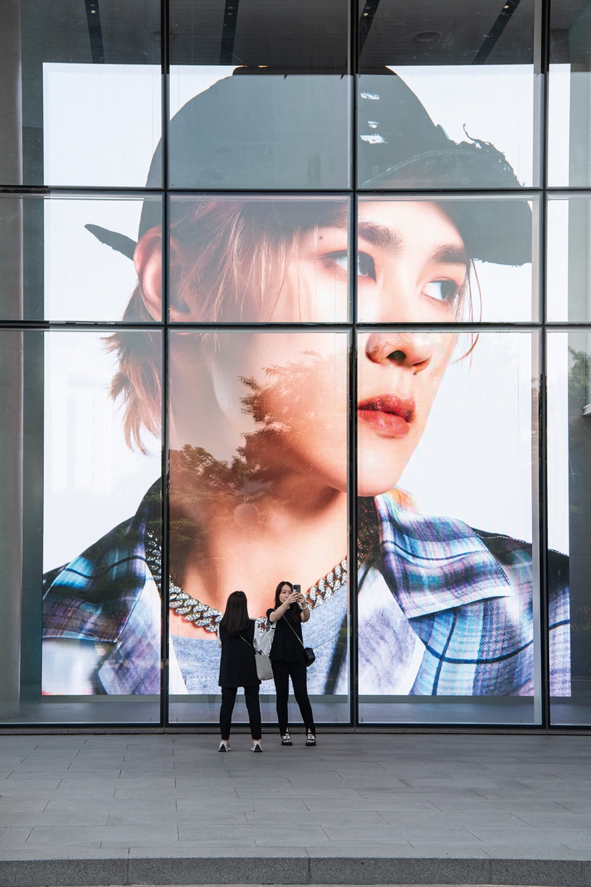 Billboard projection of a man with two women taking photos in front of it