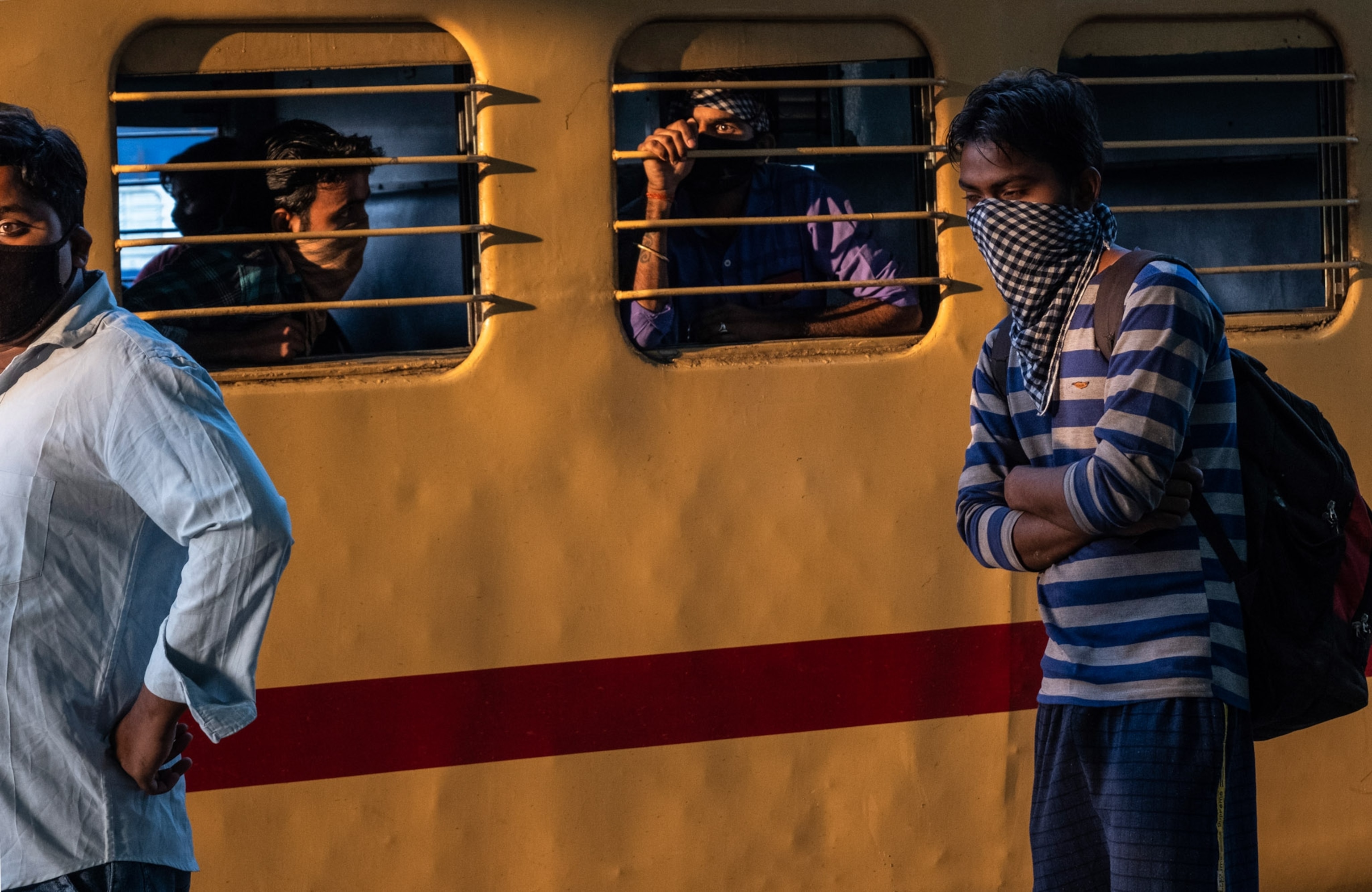 a few people looking out a train while others stand alongside the train