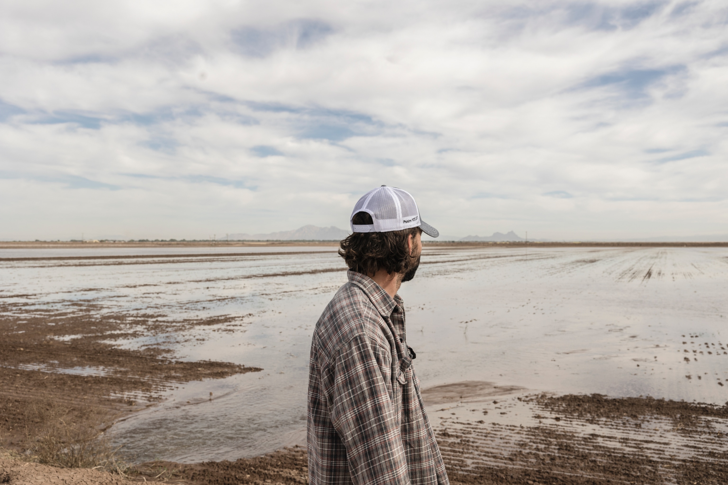 A farm manager looks out over a field being flood irrigated, monitoring for even distribution of the water. During the 2023 farm season, loss of water deliveries from the Colorado River resulted in less volume of water flowing through farms in the area. Completely reliant on groundwater, farmers’ fields take significantly longer to irrigate, creating difficulties for the local irrigation district in meeting orders in its water delivery schedule.