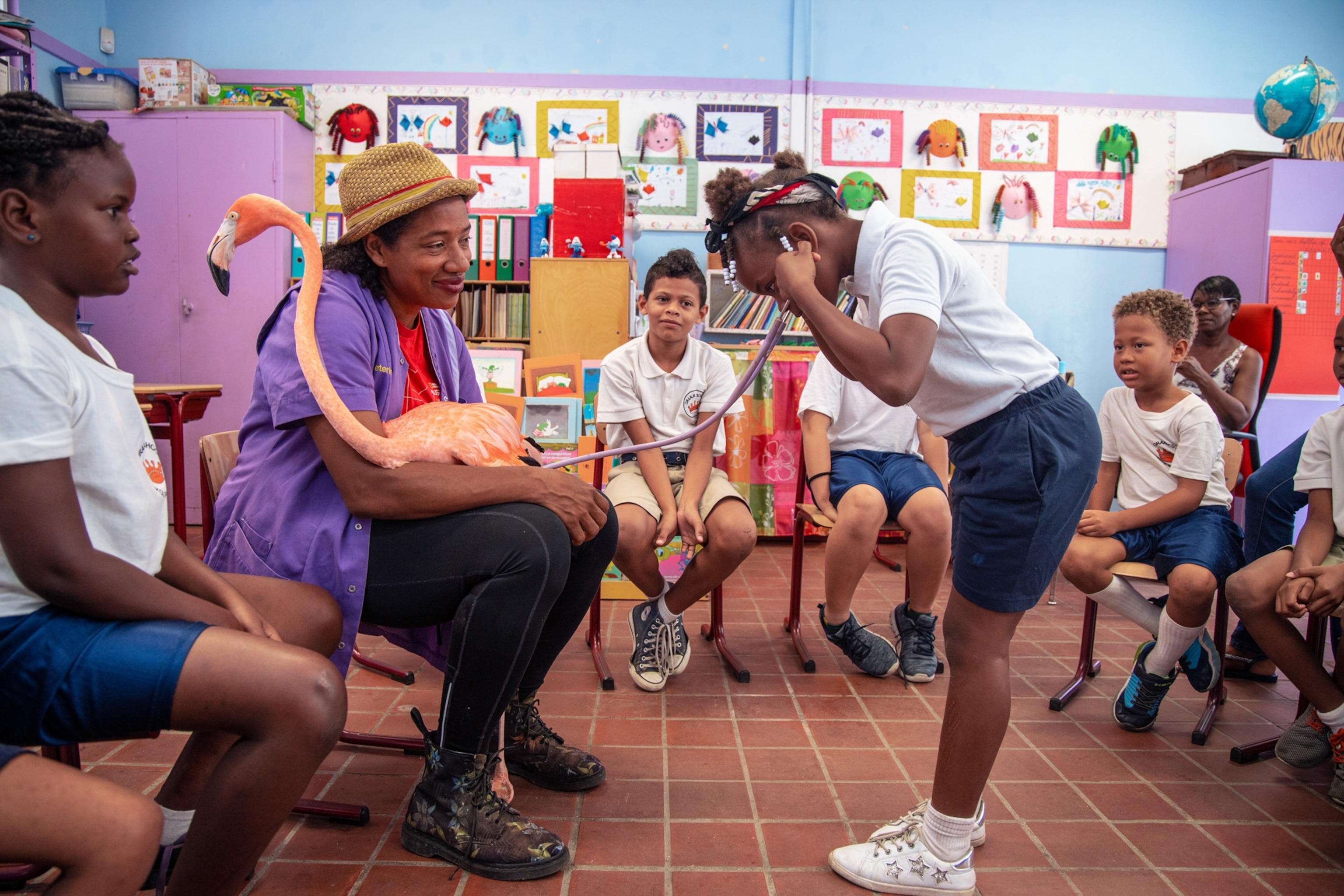 a child with a stethoscope on, listening to a flamingo's heartbeat