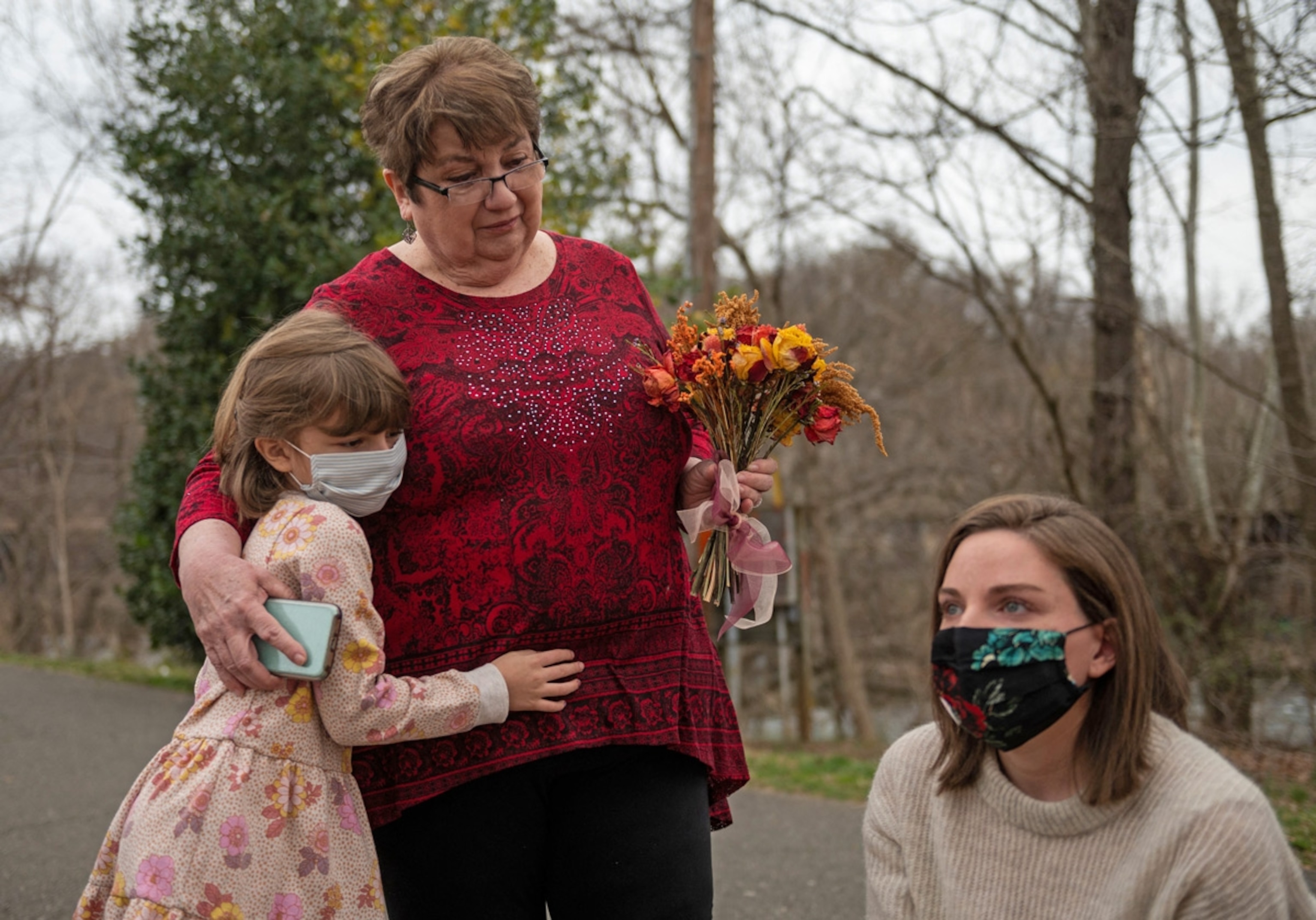 Margaux Irvine (L) the daughter of Chris Irvine, who passed from Covid-19 in January hugs her grandmother Sue, as her mother Carly (R) looks on near the James river in Lynchburg, Virginia on March 13, 2021.