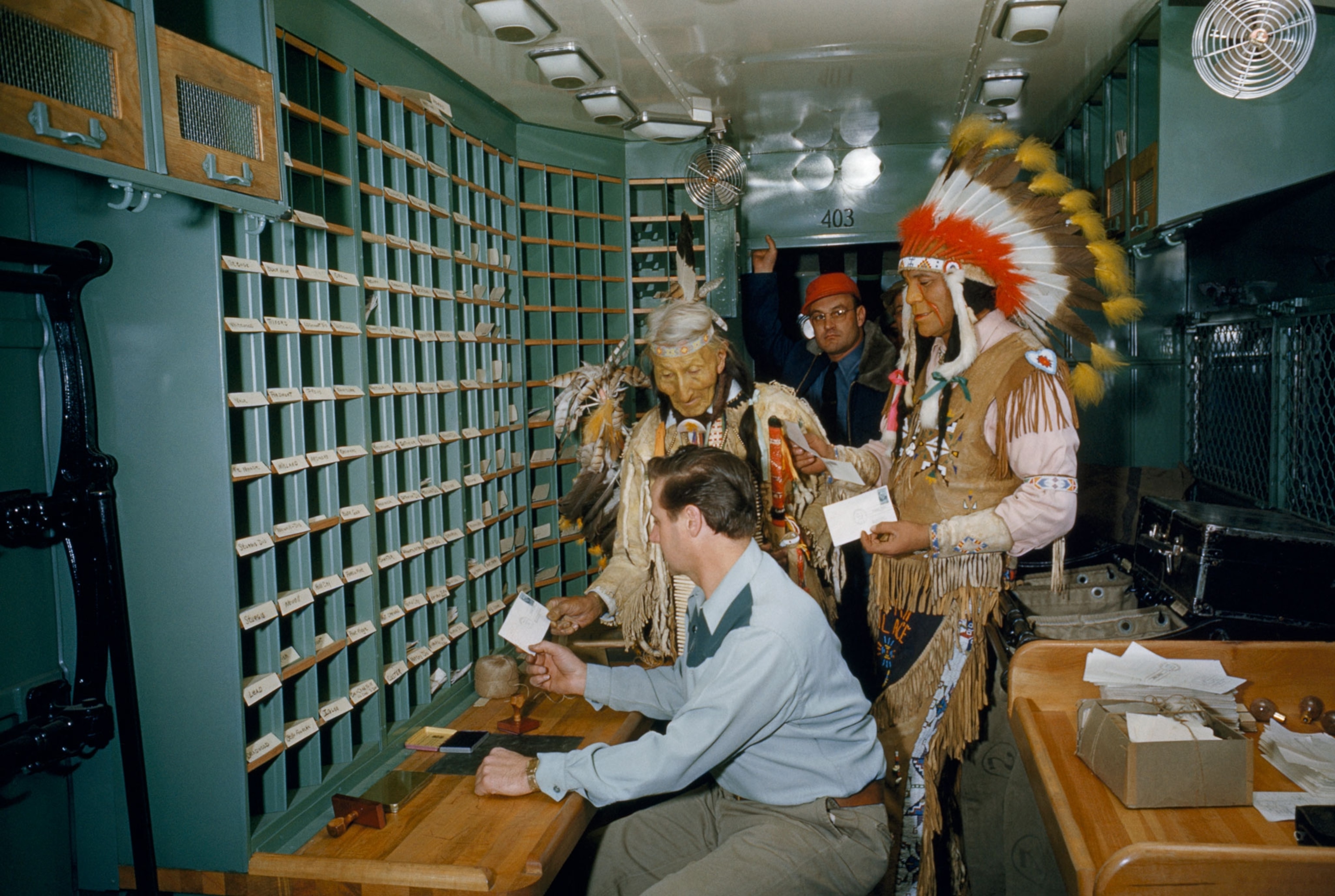 Native Americans in traditional dress using a post office