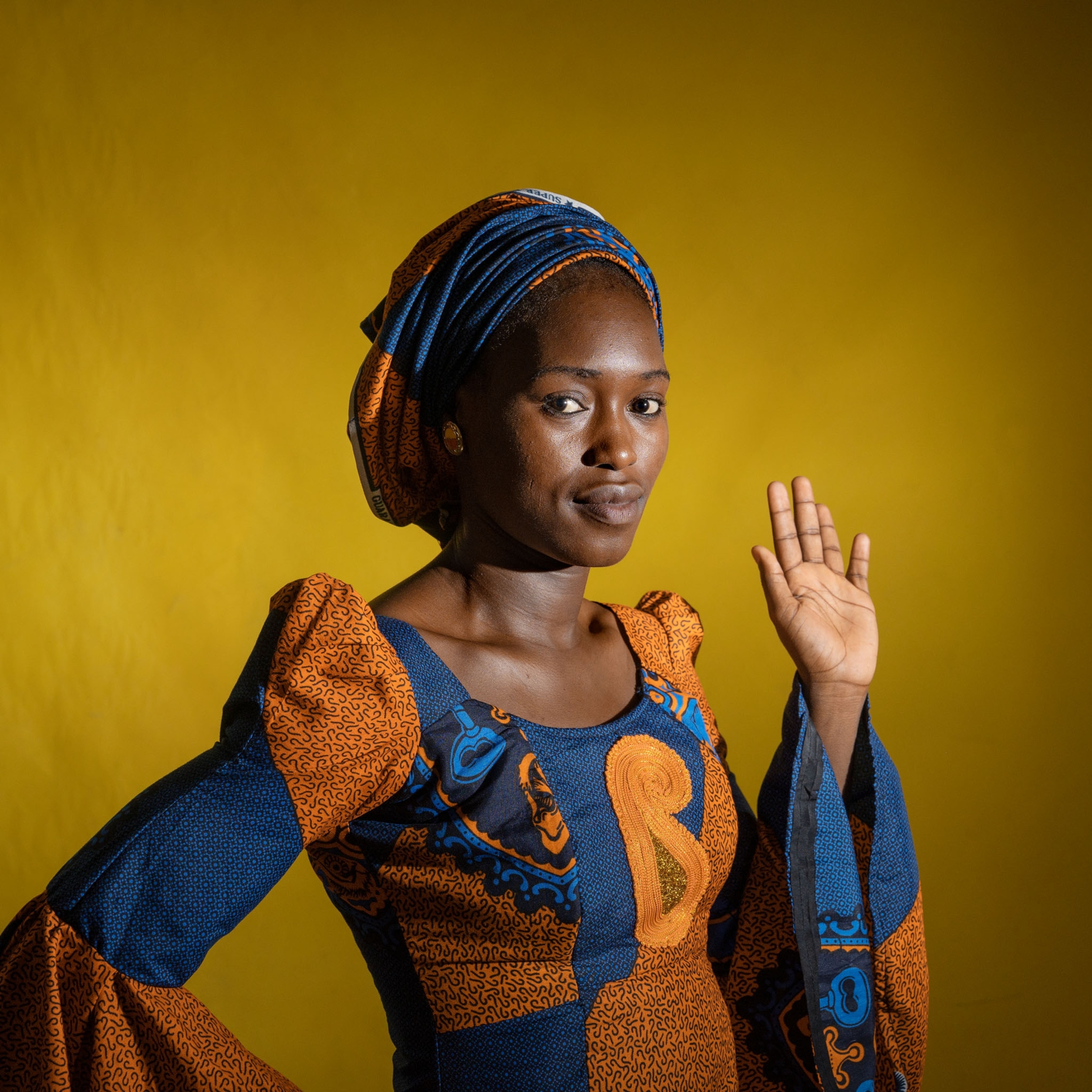 a woman holding her hand up and standing for a portrait