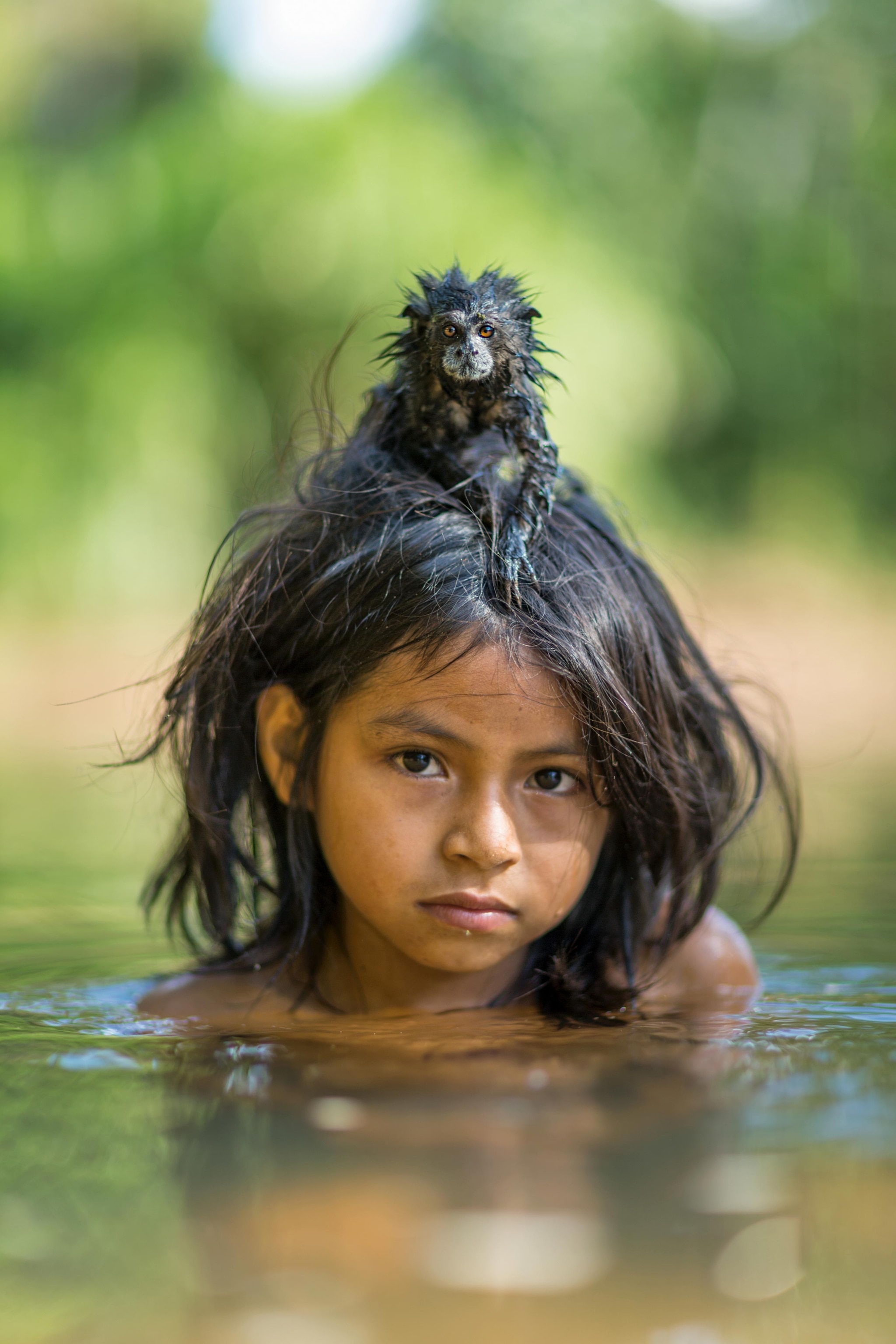 a girl with a pet tamarin on her head, in Manú National Park, Peru