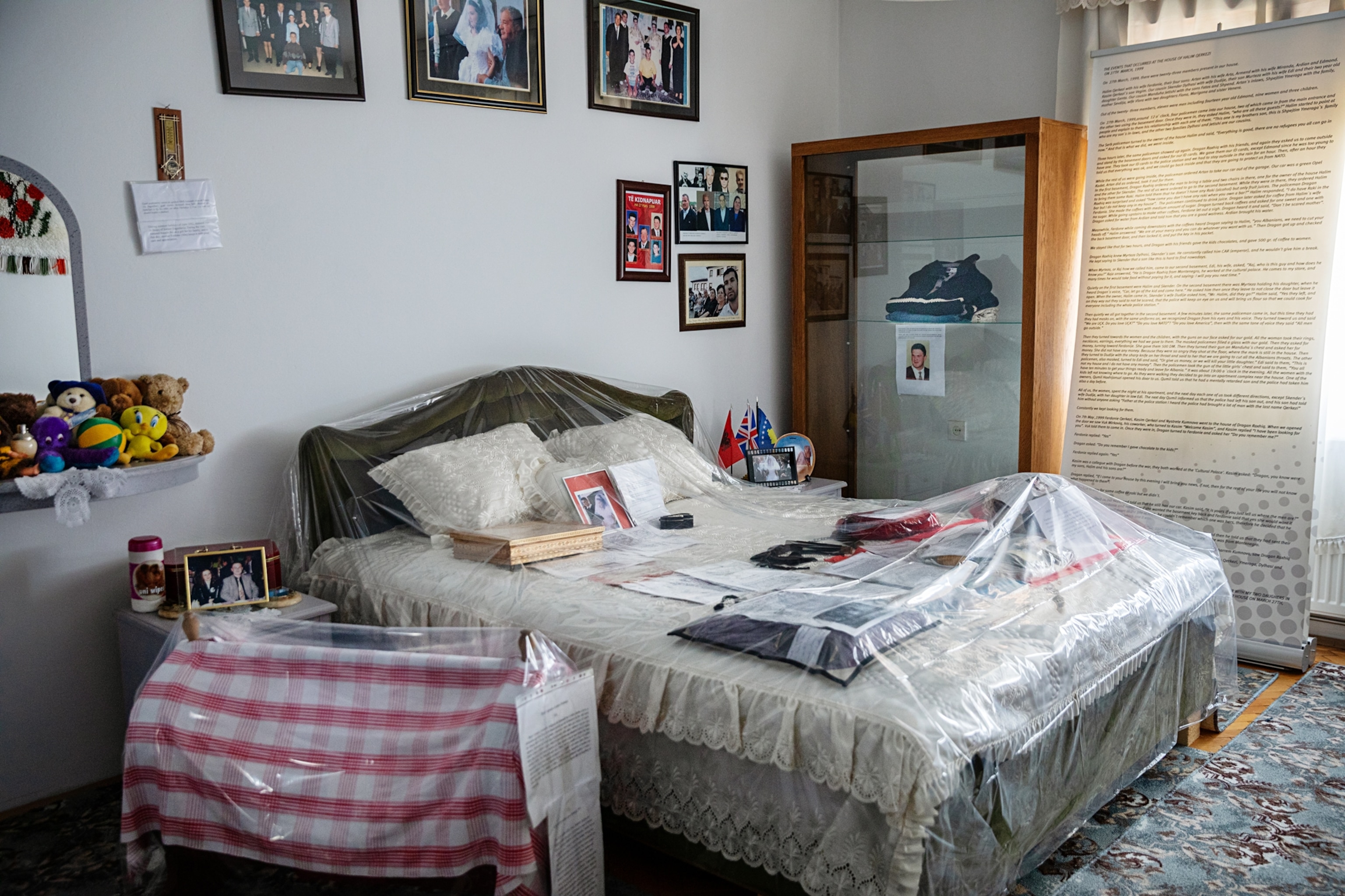 A bedroom with one bed and a baby's cradle encased in protective plastic.