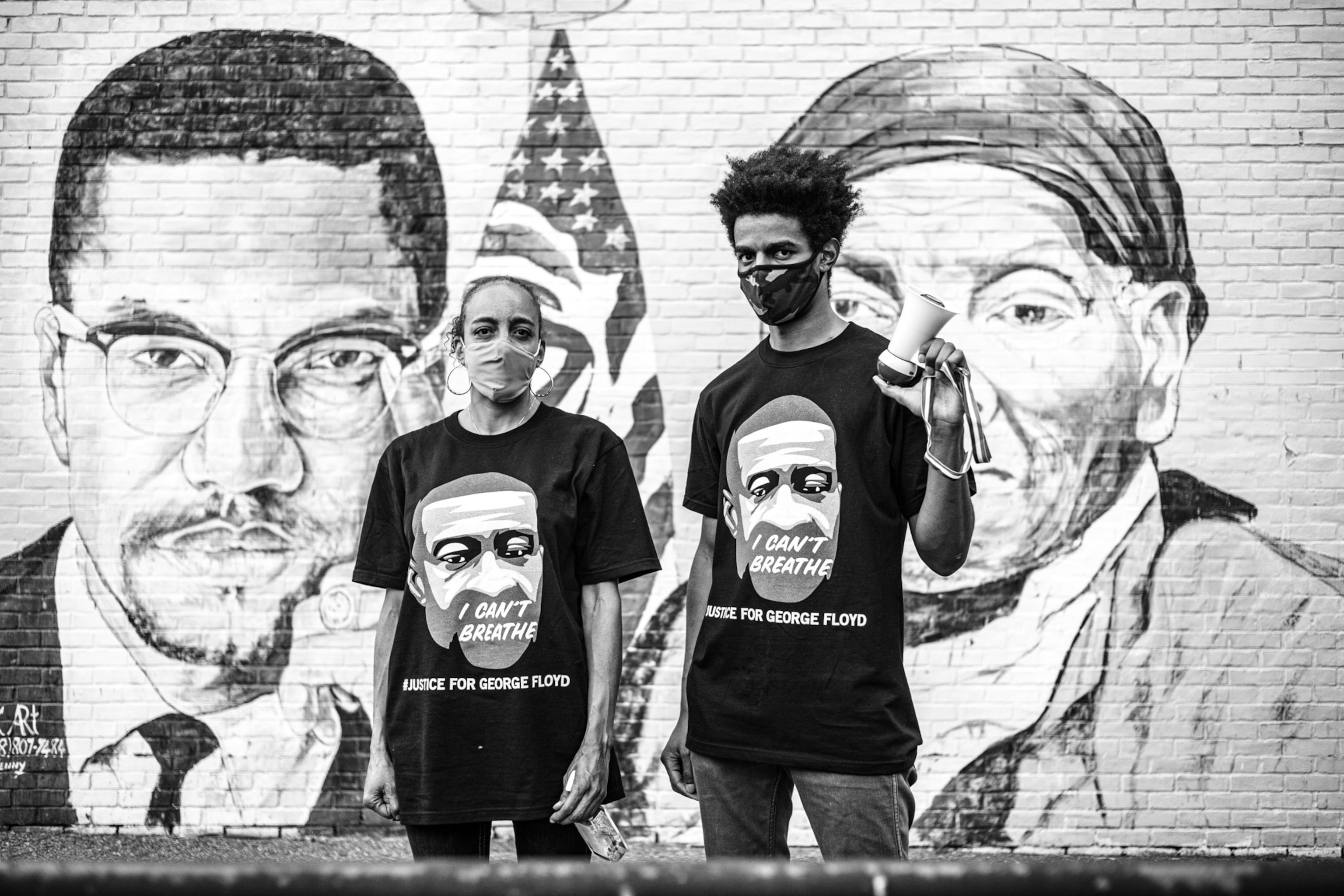 two people standing in front of a mural of Harriet Tubman and Malcom X
