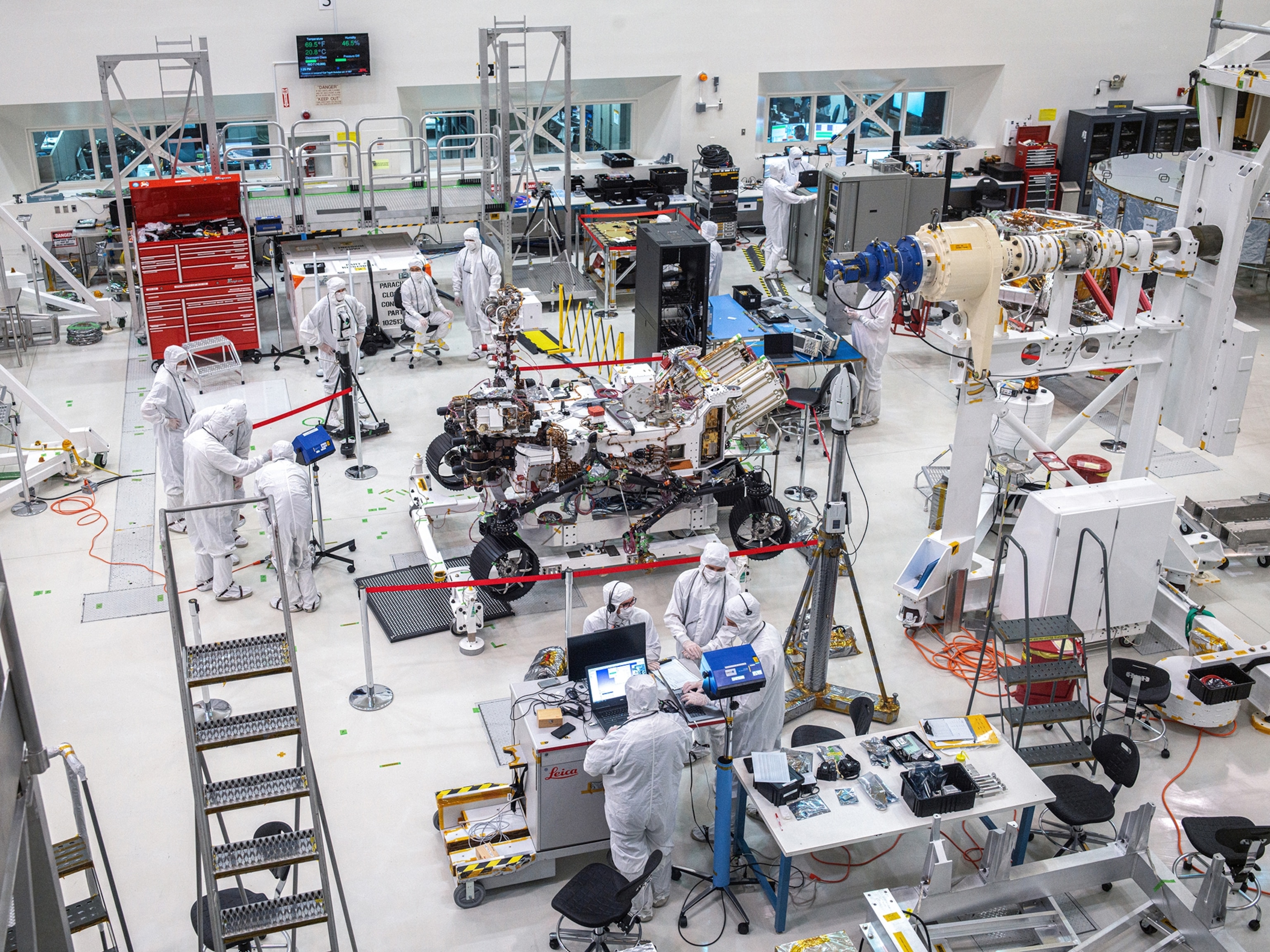 Picture from above of laboratory full of equepments, people in white and rover in the center.