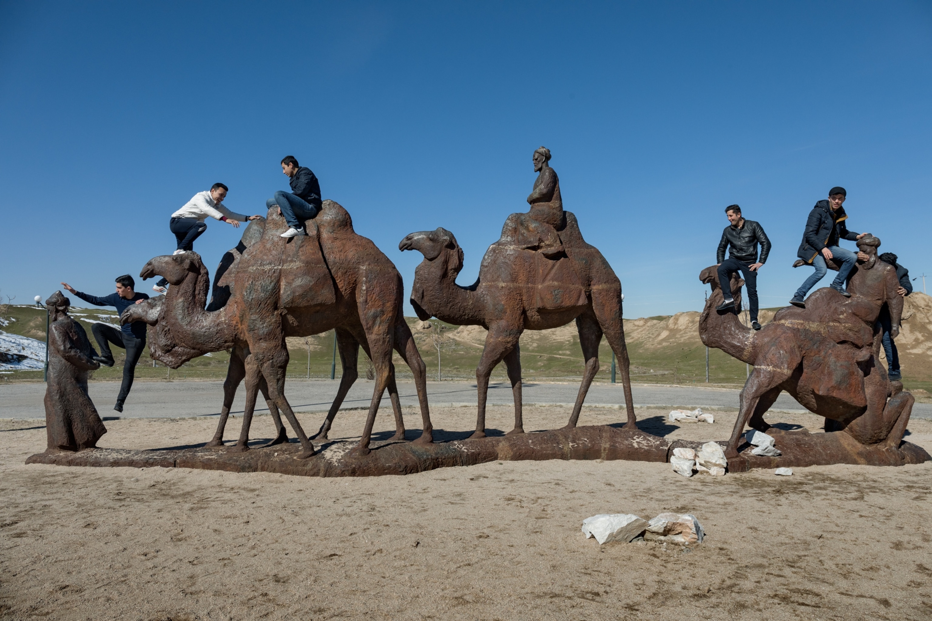 local tourist climbing on bronze statues of camels in the desert