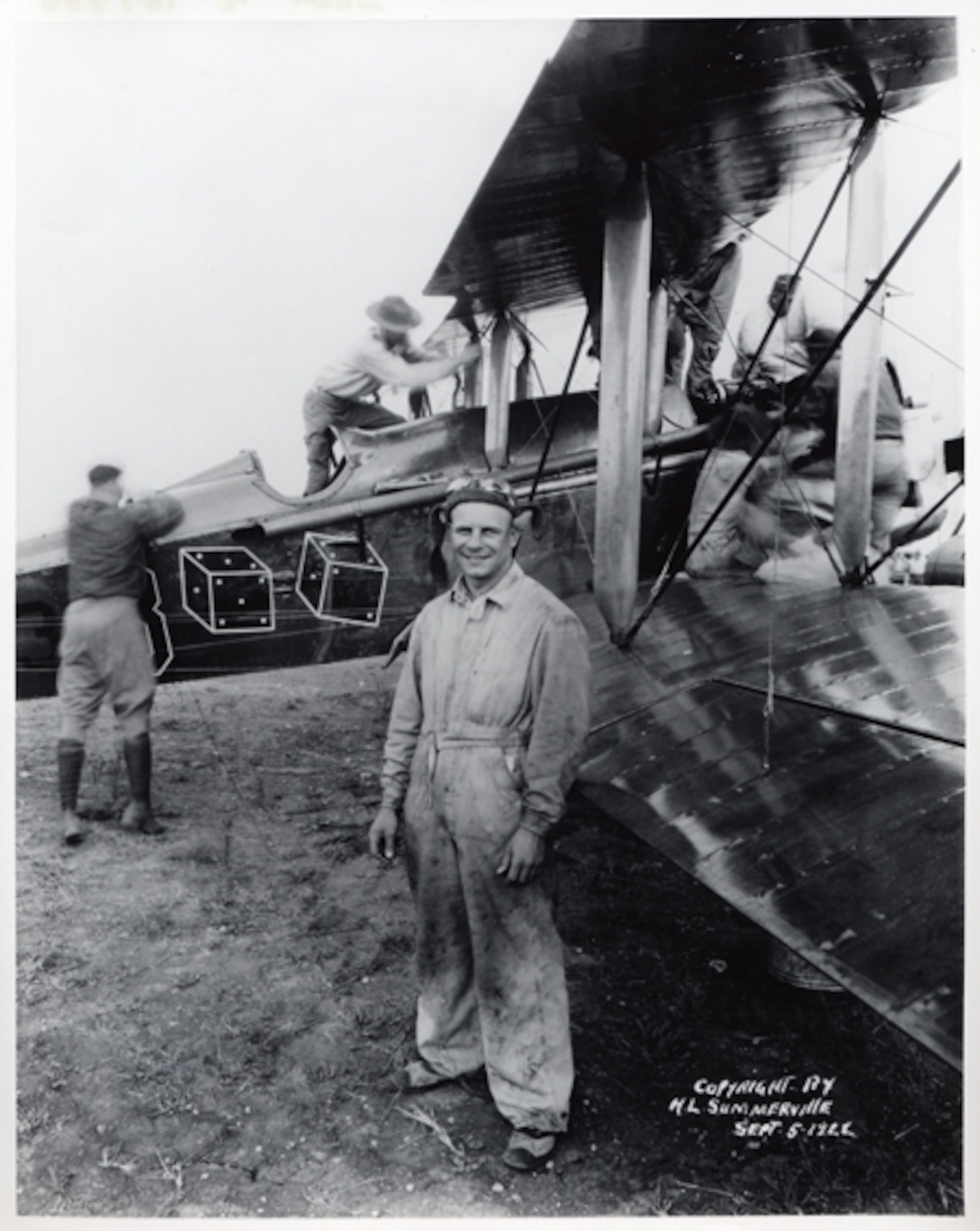 a 1920s pilot in front of his plane.