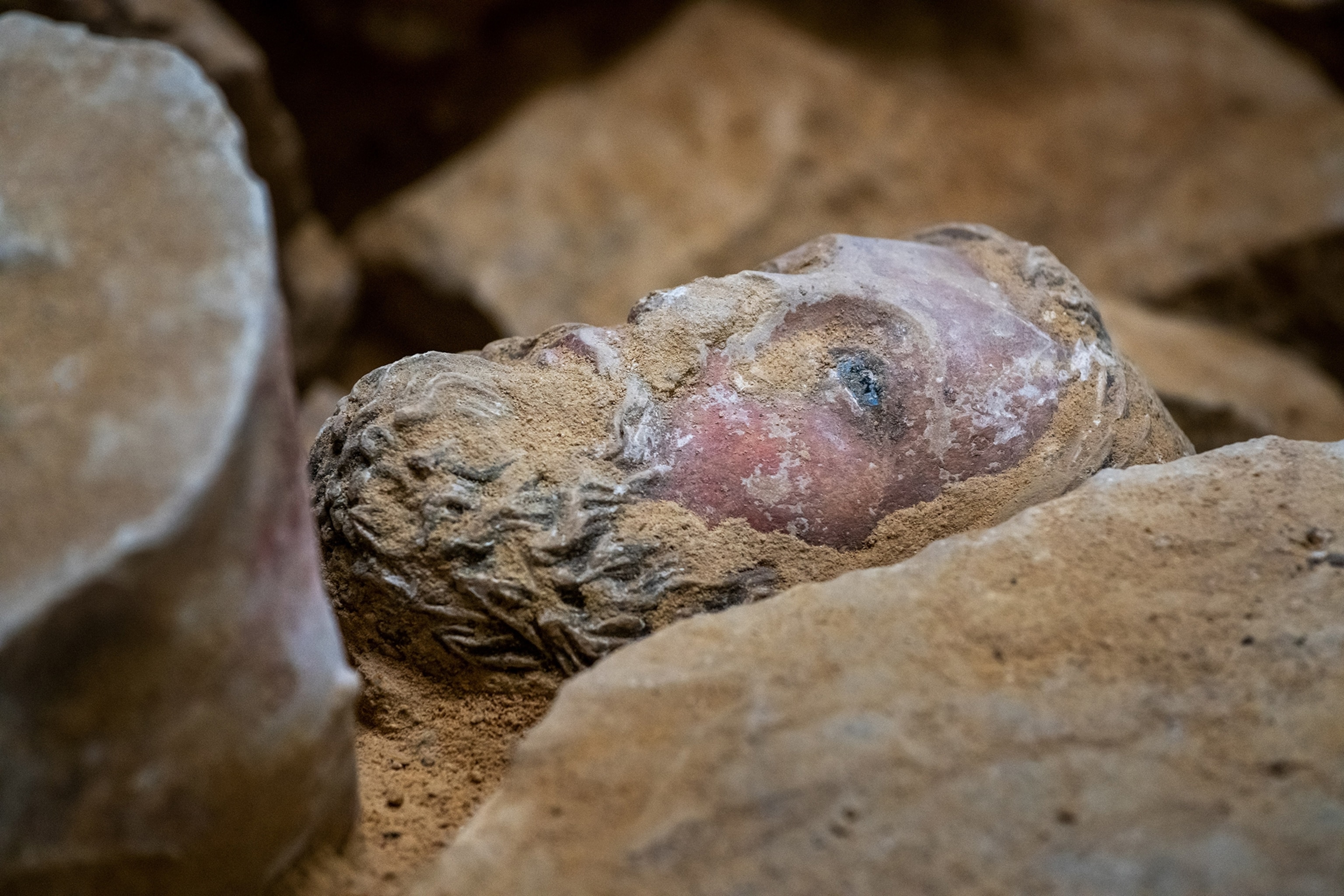 Excavation of a head statue wedged between rocks in the Notre-Dame de Paris.