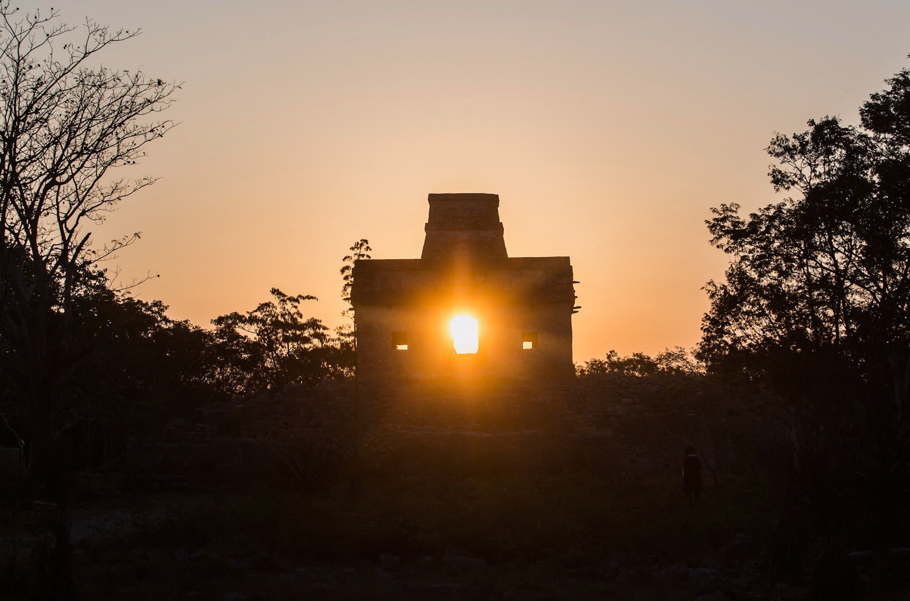 The sun shines straight through the window openings of a stone temple.