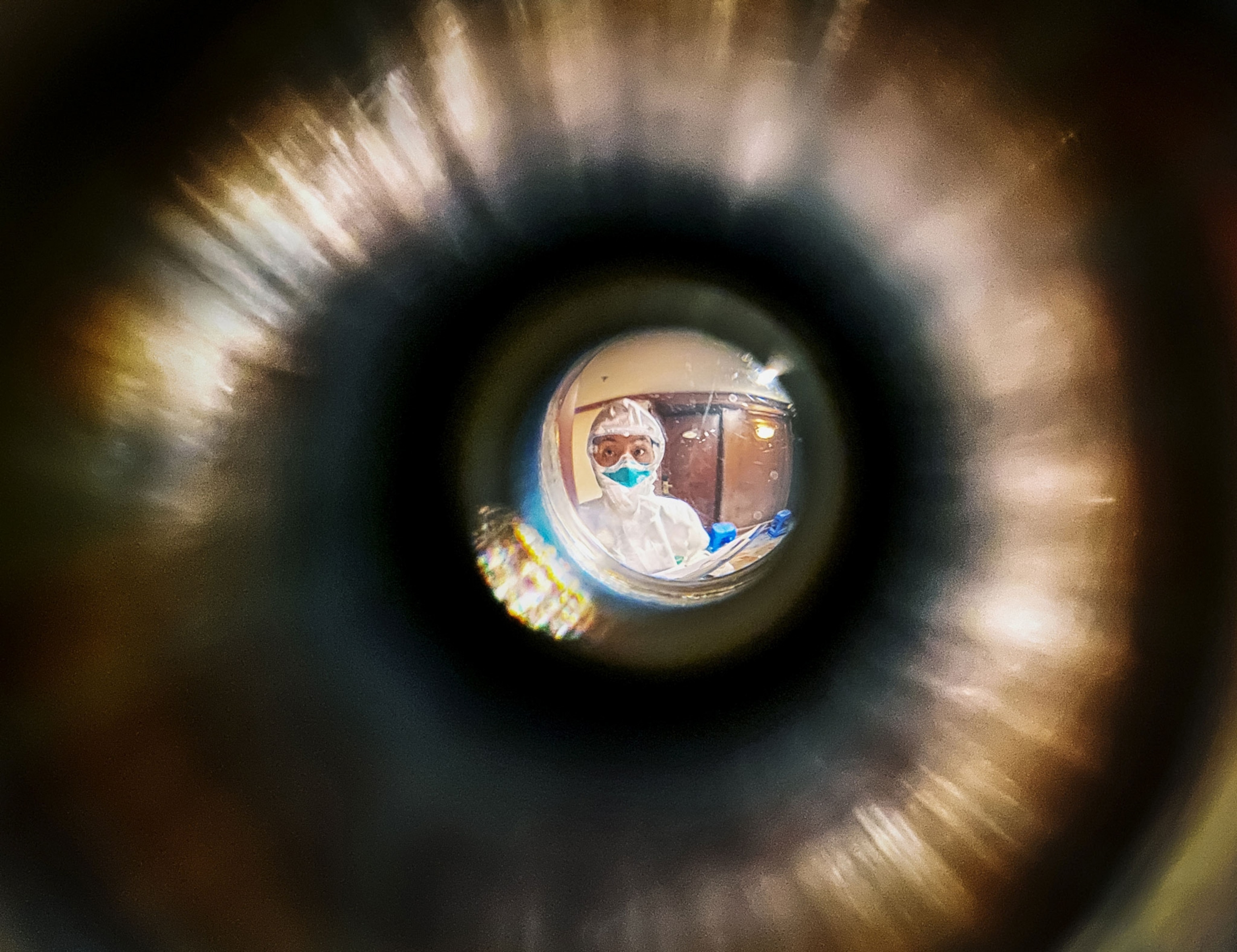 a healthcare worker reads someones temperature through a hotel room door during quarantine in China