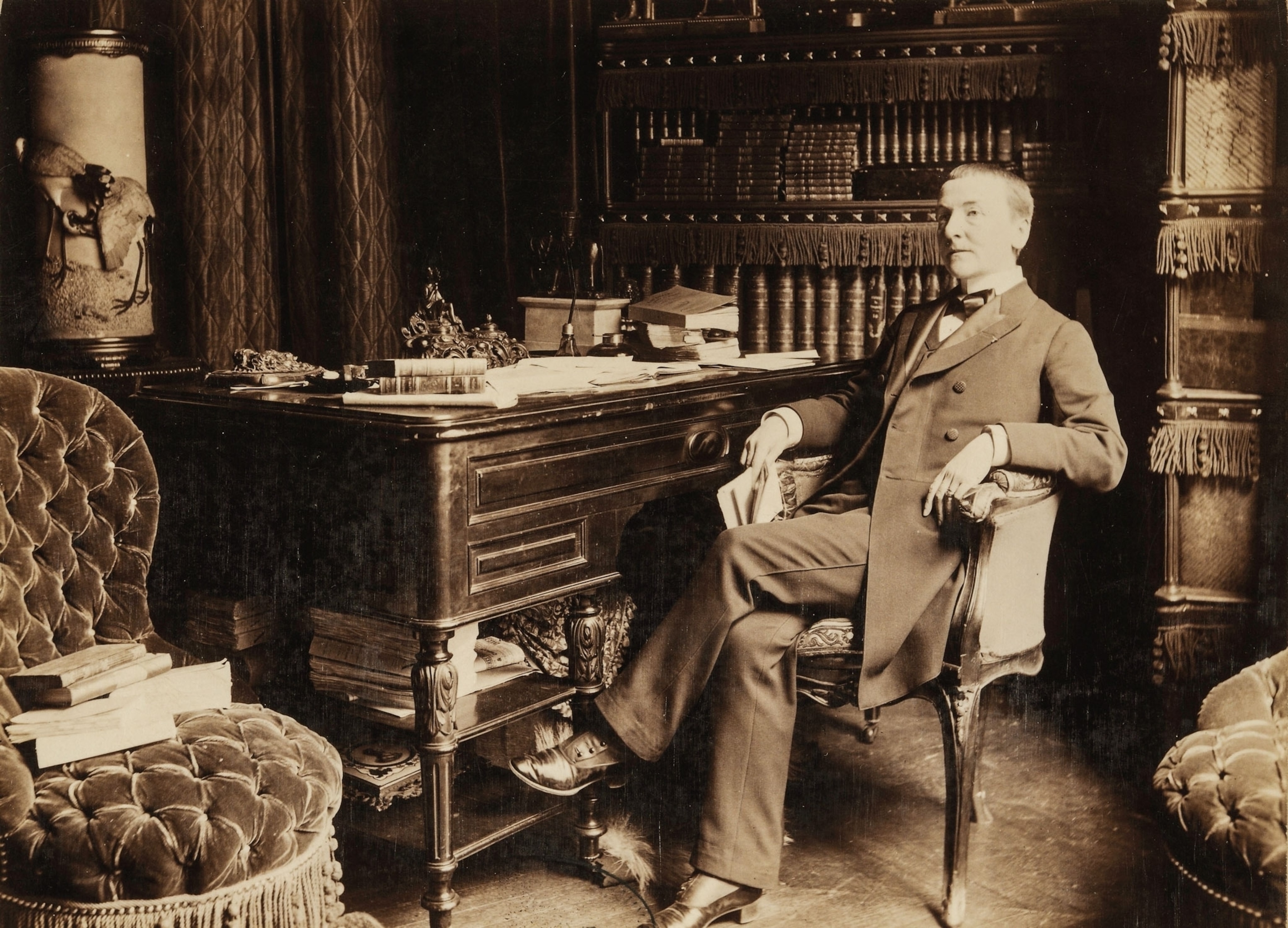 A person wearing a three piece suit sits in a chair