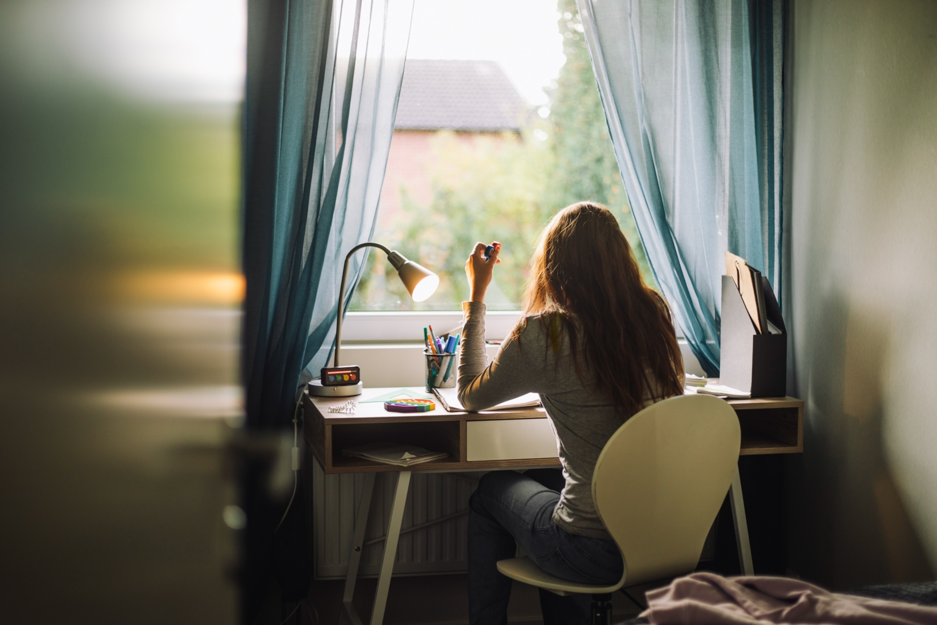 Rear view of a young woman doing work at desk while fidgeting