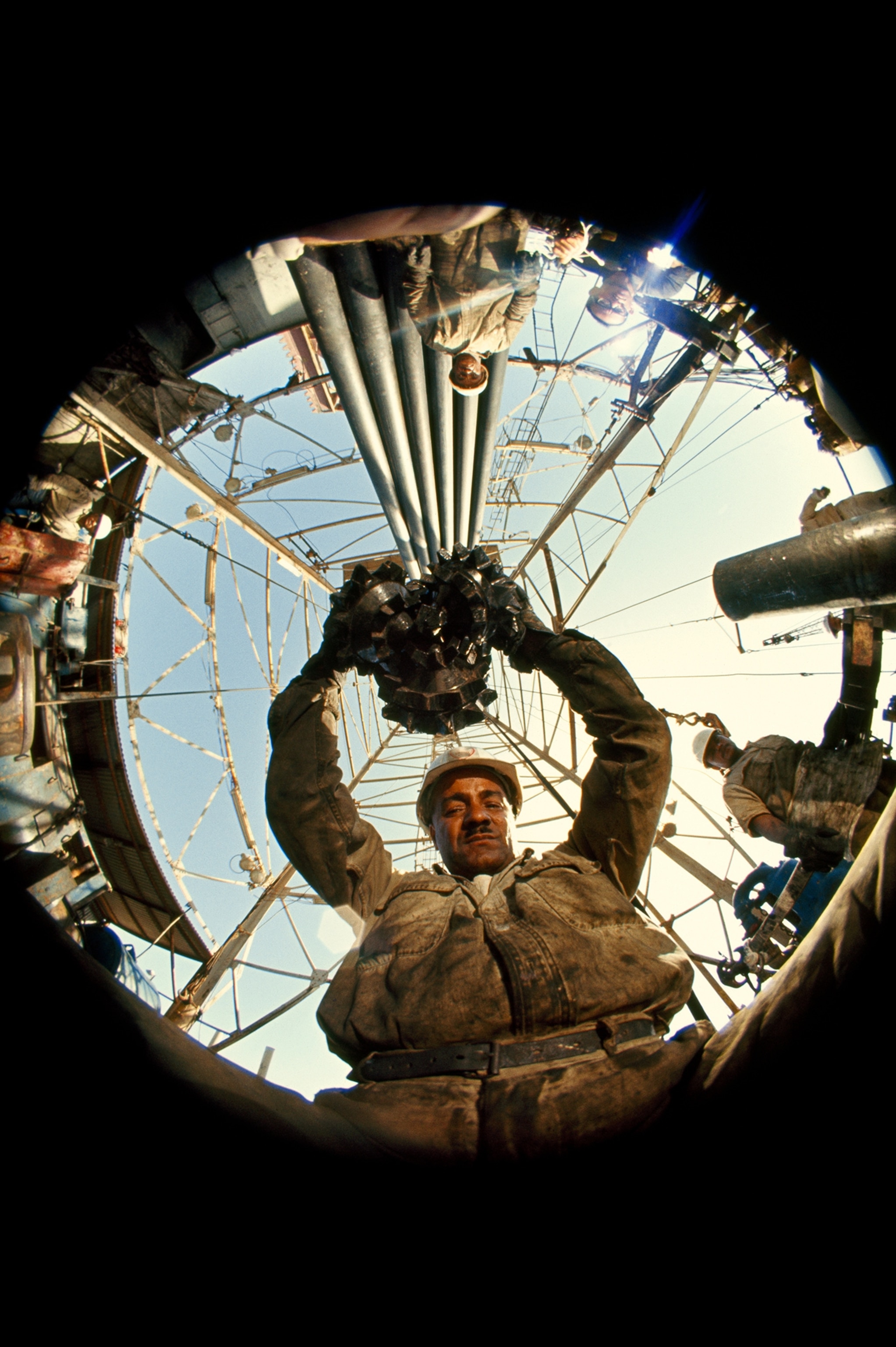 Oil worker maneuvers a diamond-toothed drill. Safaniya, Saudi Arabia.