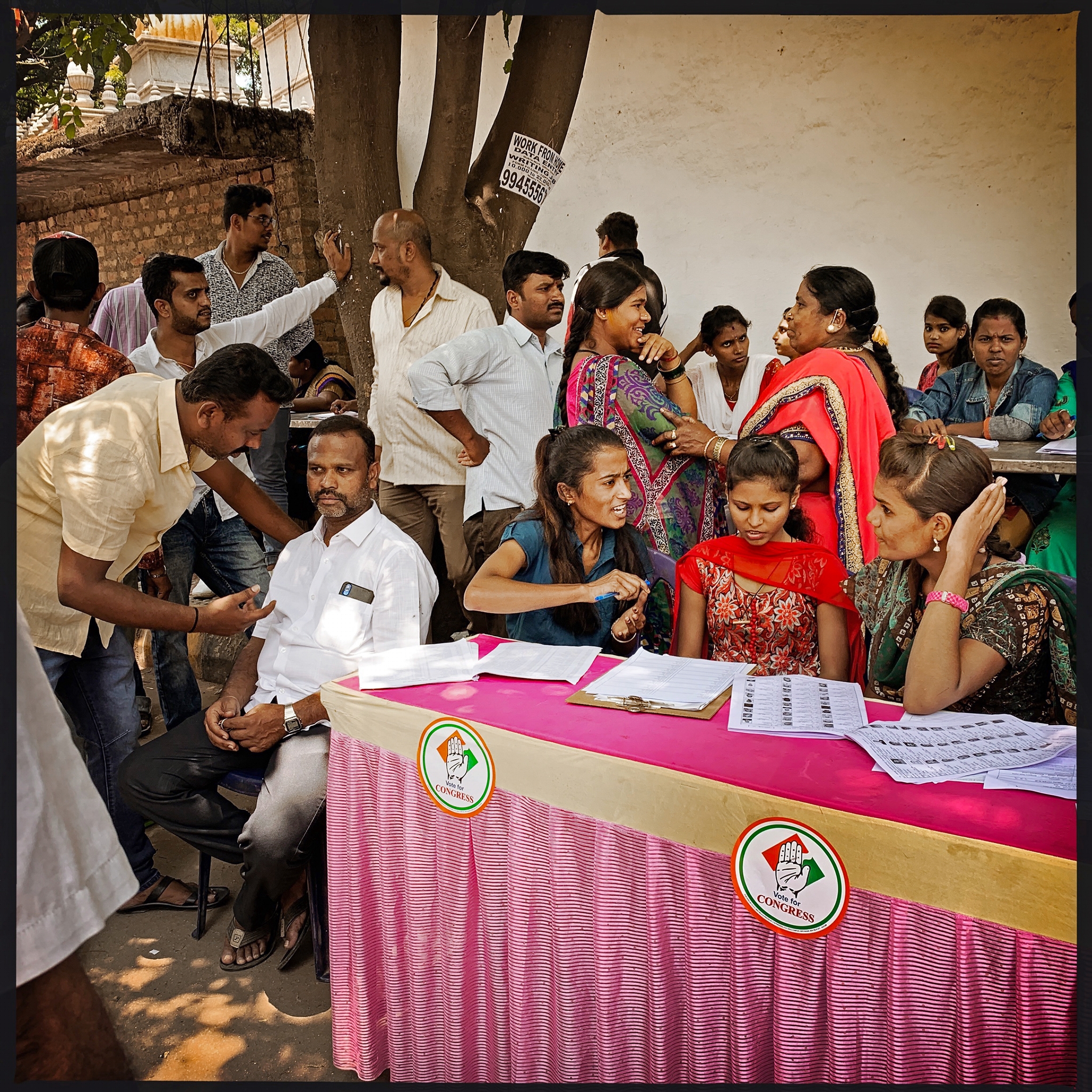 a group of people discussing around a pink check-in table