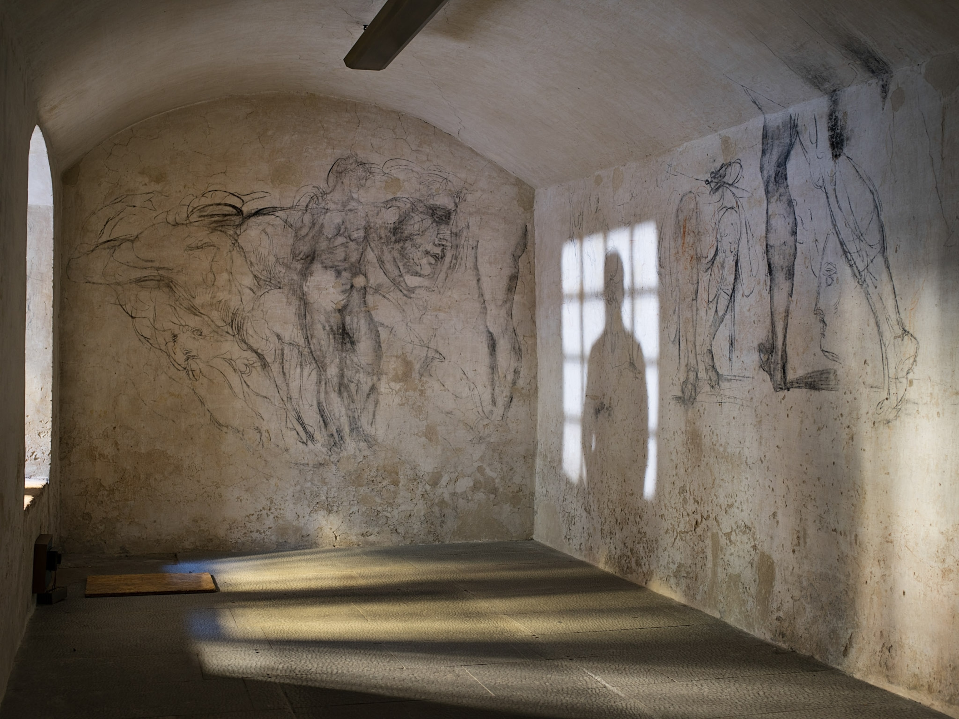 A room with drawings in charcoal on the wall.