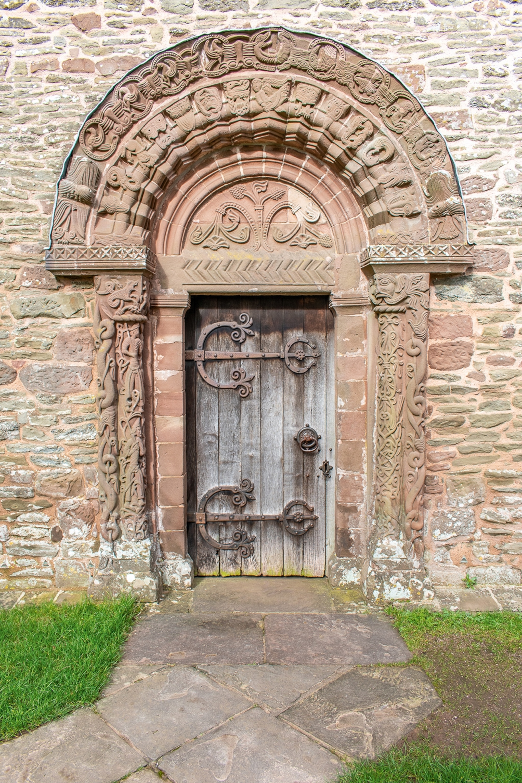 Shot of a medieval wooden door encased by decoratively chiselled stone in an old brick building.