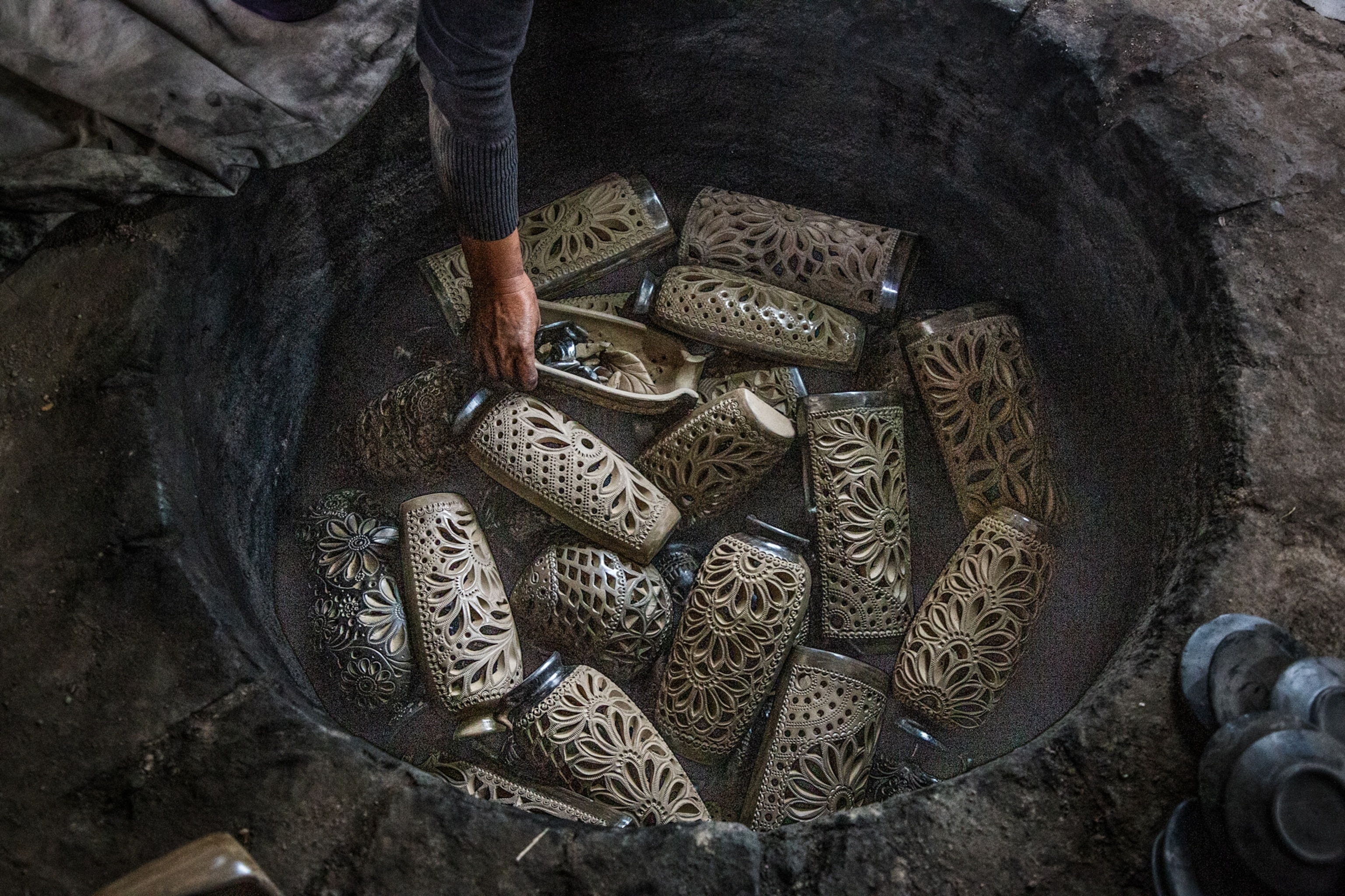 Graciela Simon López placing the pottery pieces in a stone and adobe kiln
