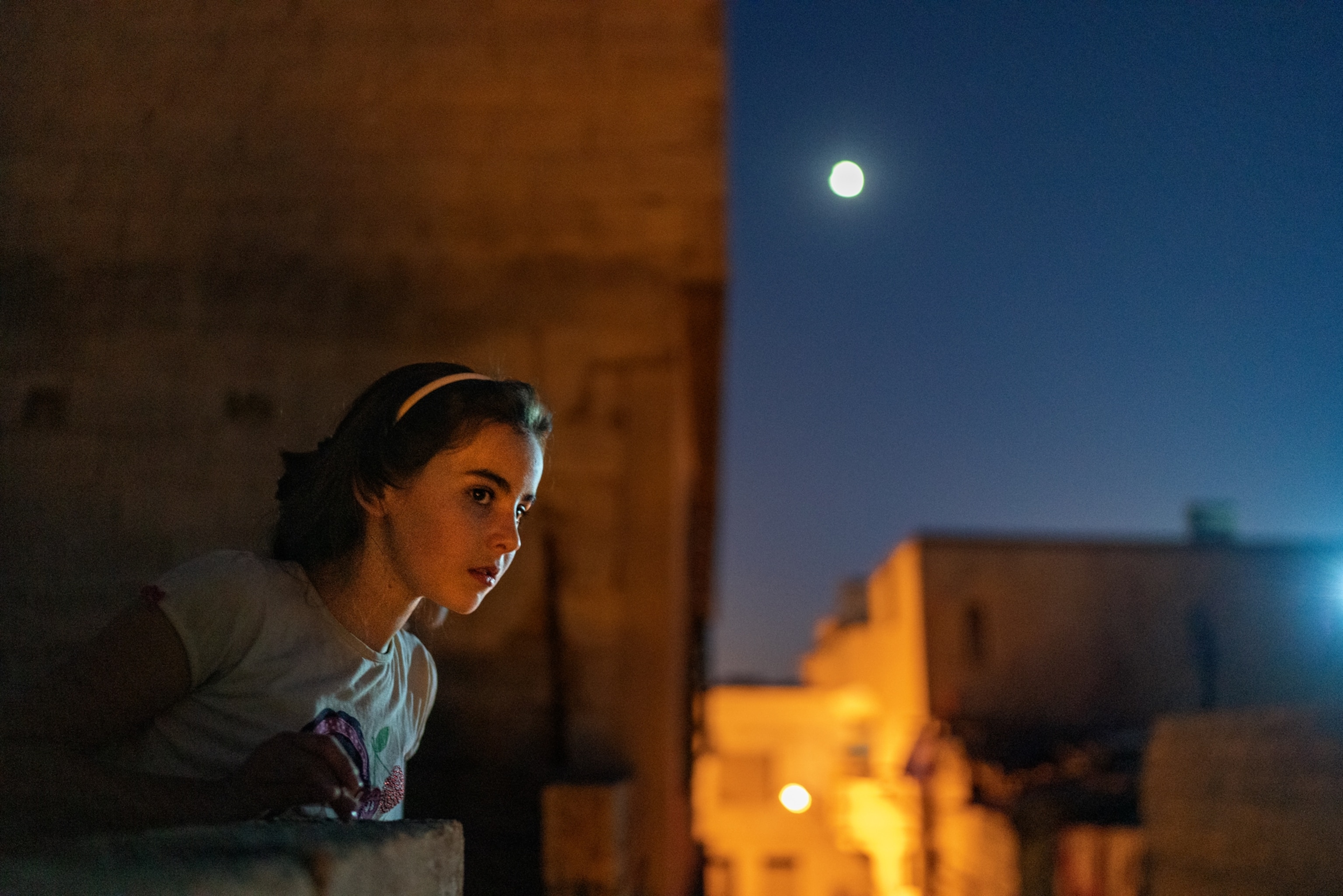A young girl looking over a balcony at dusk