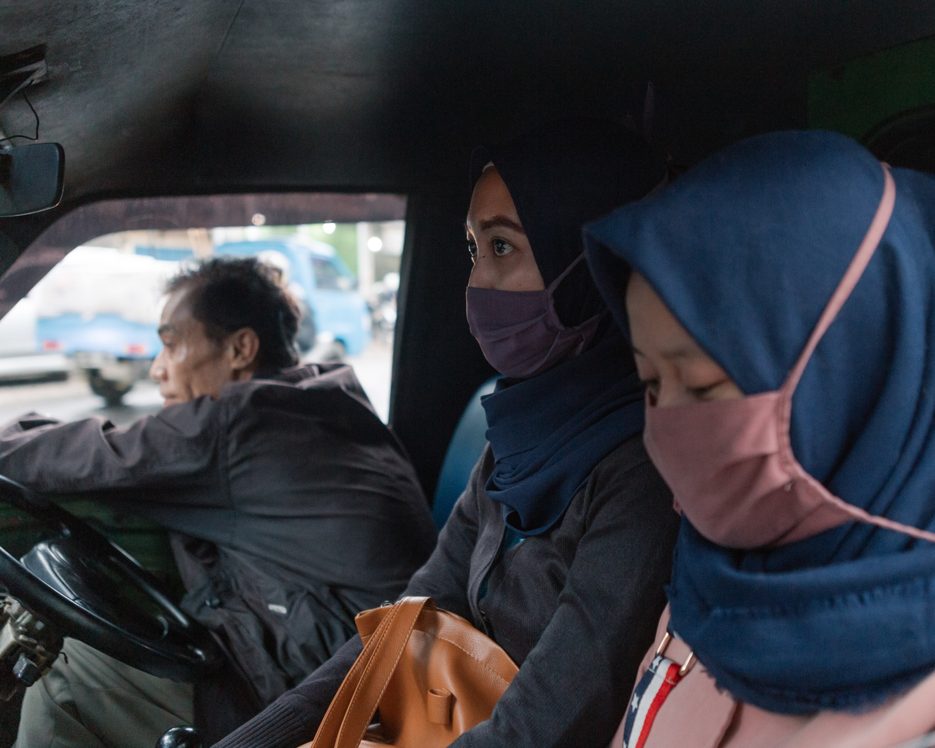 two women wearing face masks in the passenger seat of a minibus