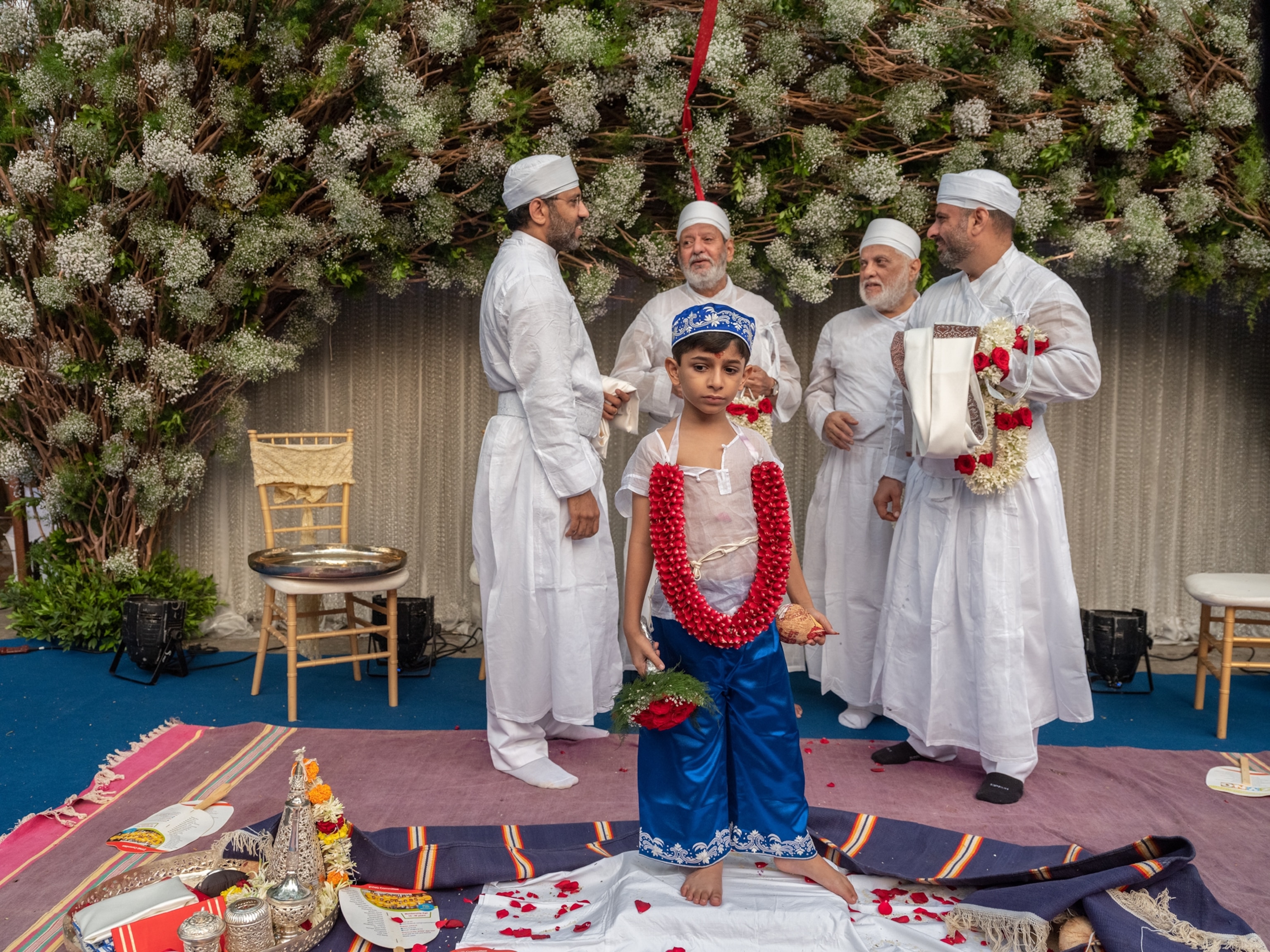 Aaria Boomla is walking in front of individuals standing between two sculptures as they exit the Iranshah Atash Bahram