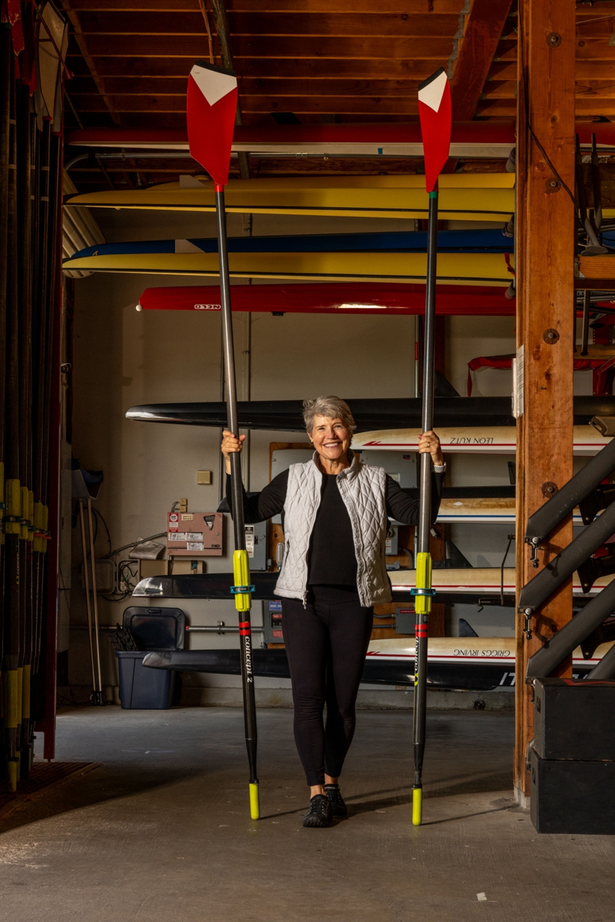 A woman holds two large ors that tower over her body.