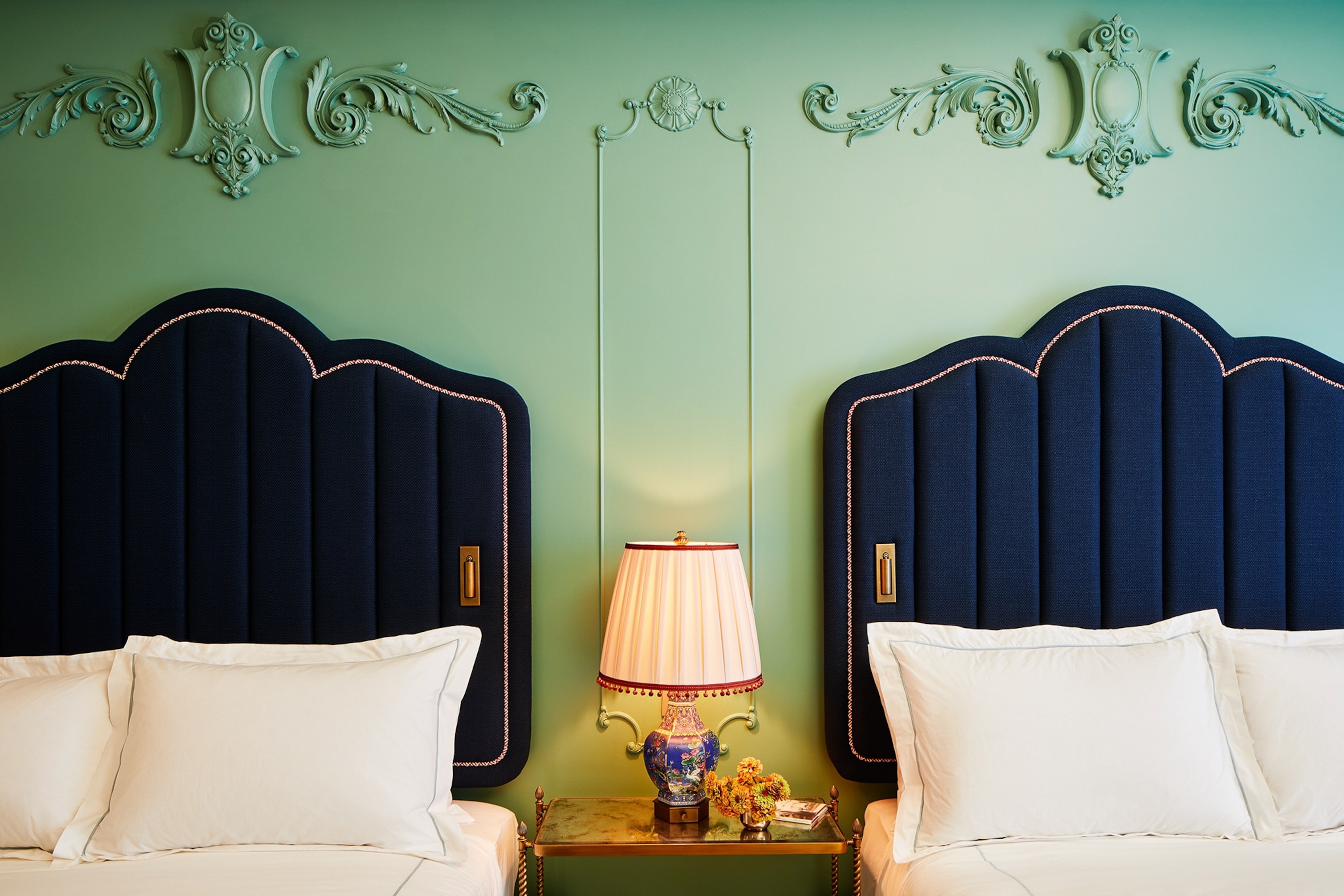 Hotel navy headboards and white linens with flower designs engraved on the wall
