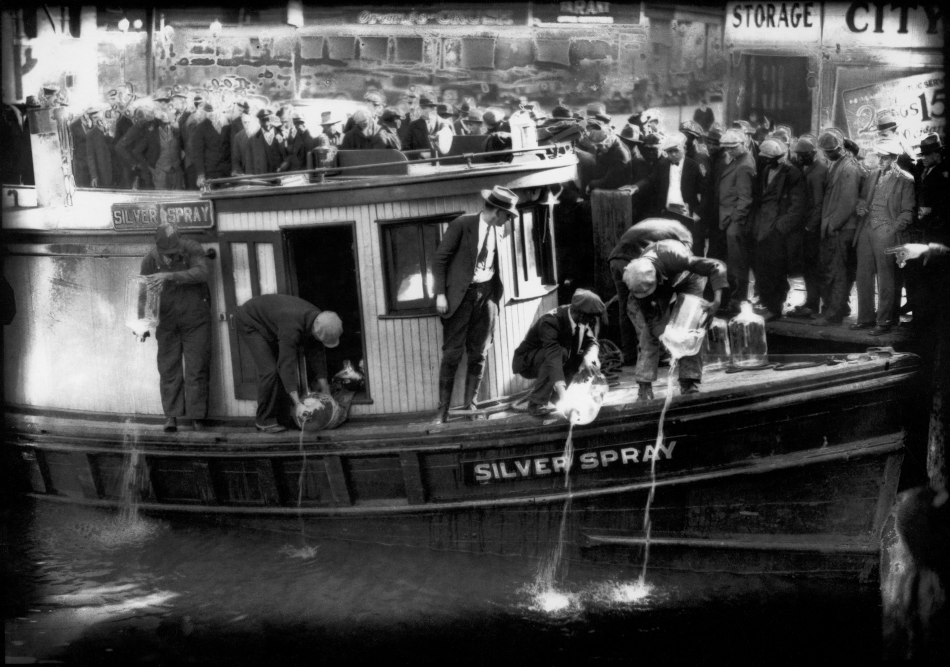 Large bottles of liquid are being poured out of a boat.