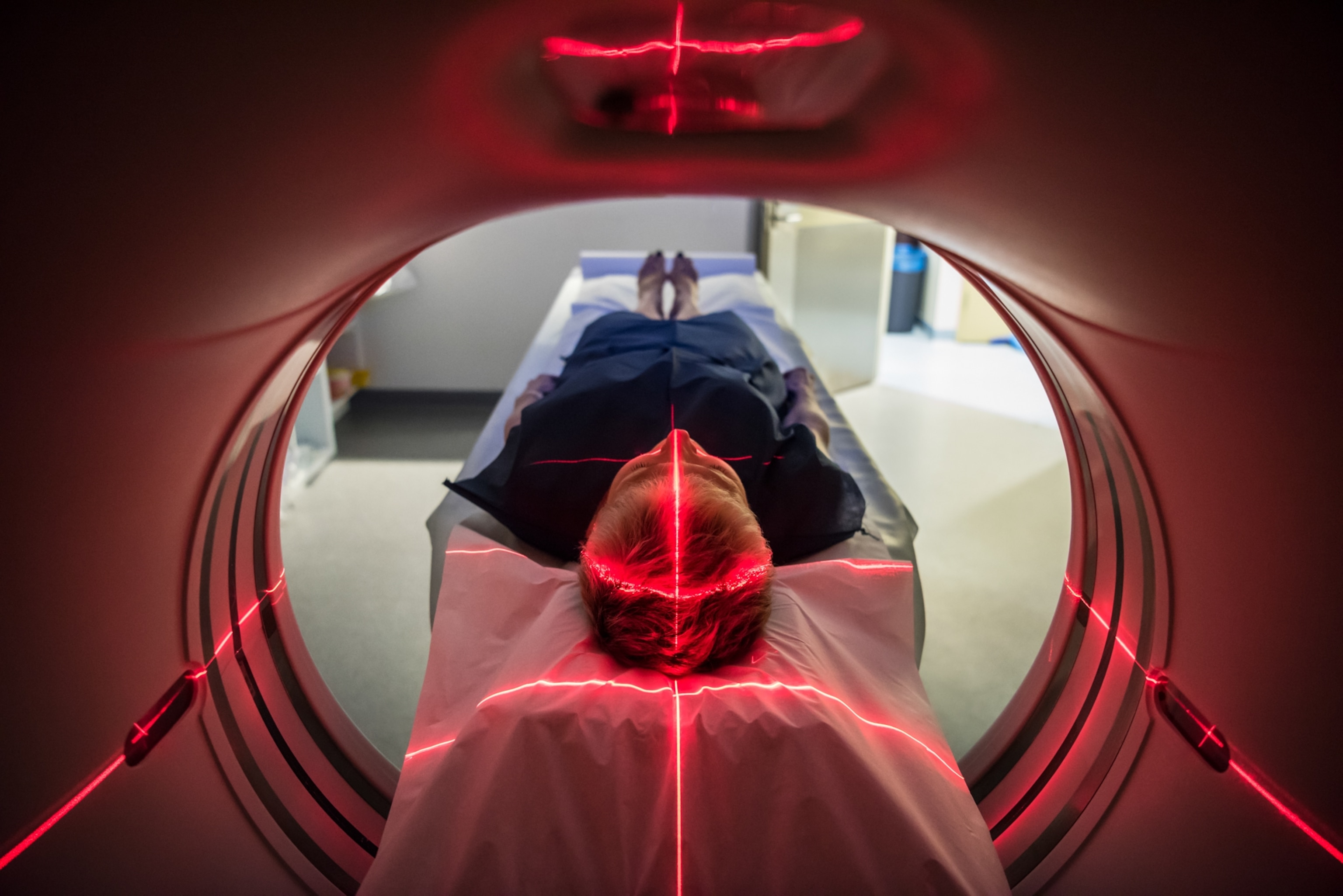 A view inside a CT scanner as a patient is positioned using red projected lines of light.