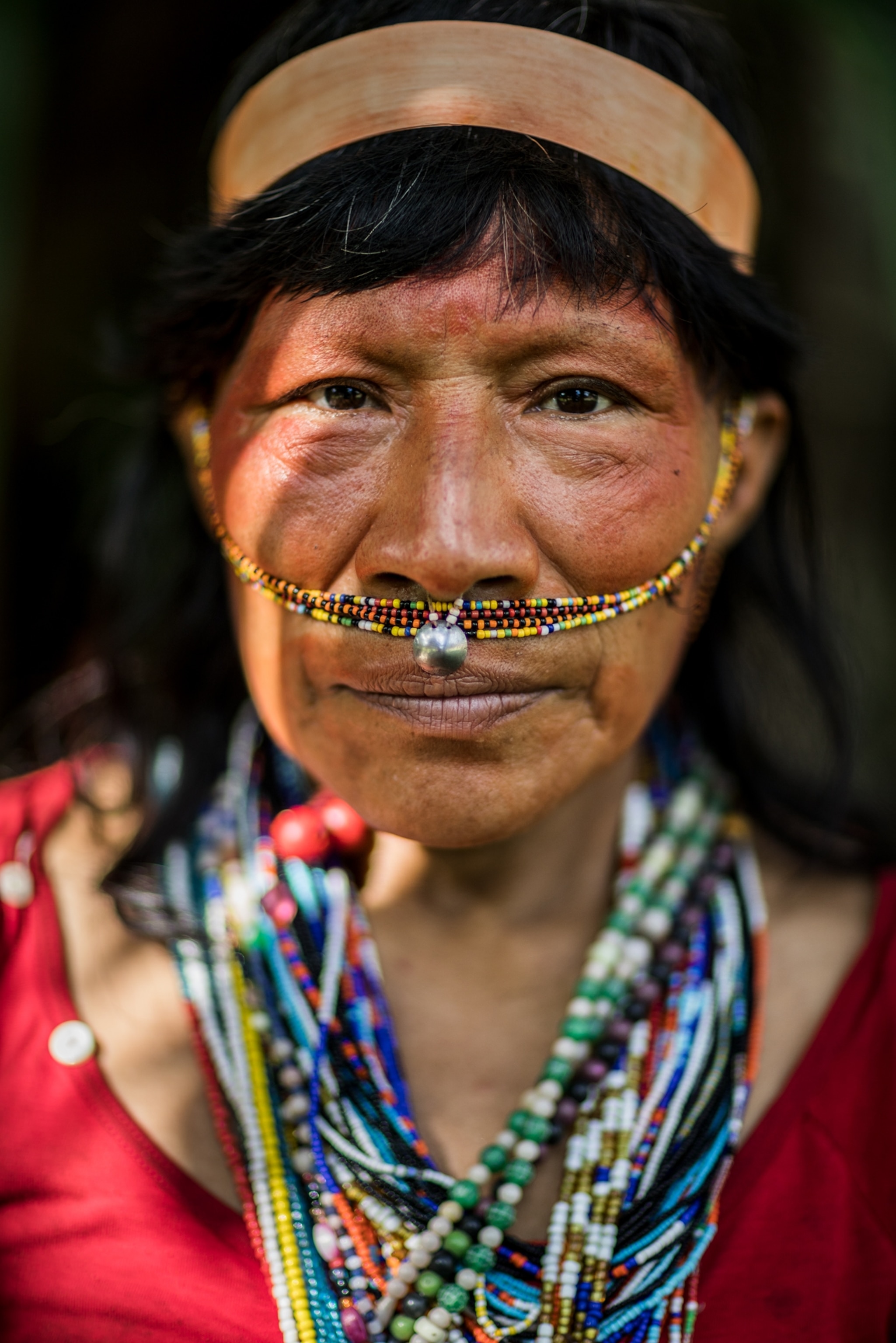 a woman wearing beads on her neck and beads on her face standing for a portrait