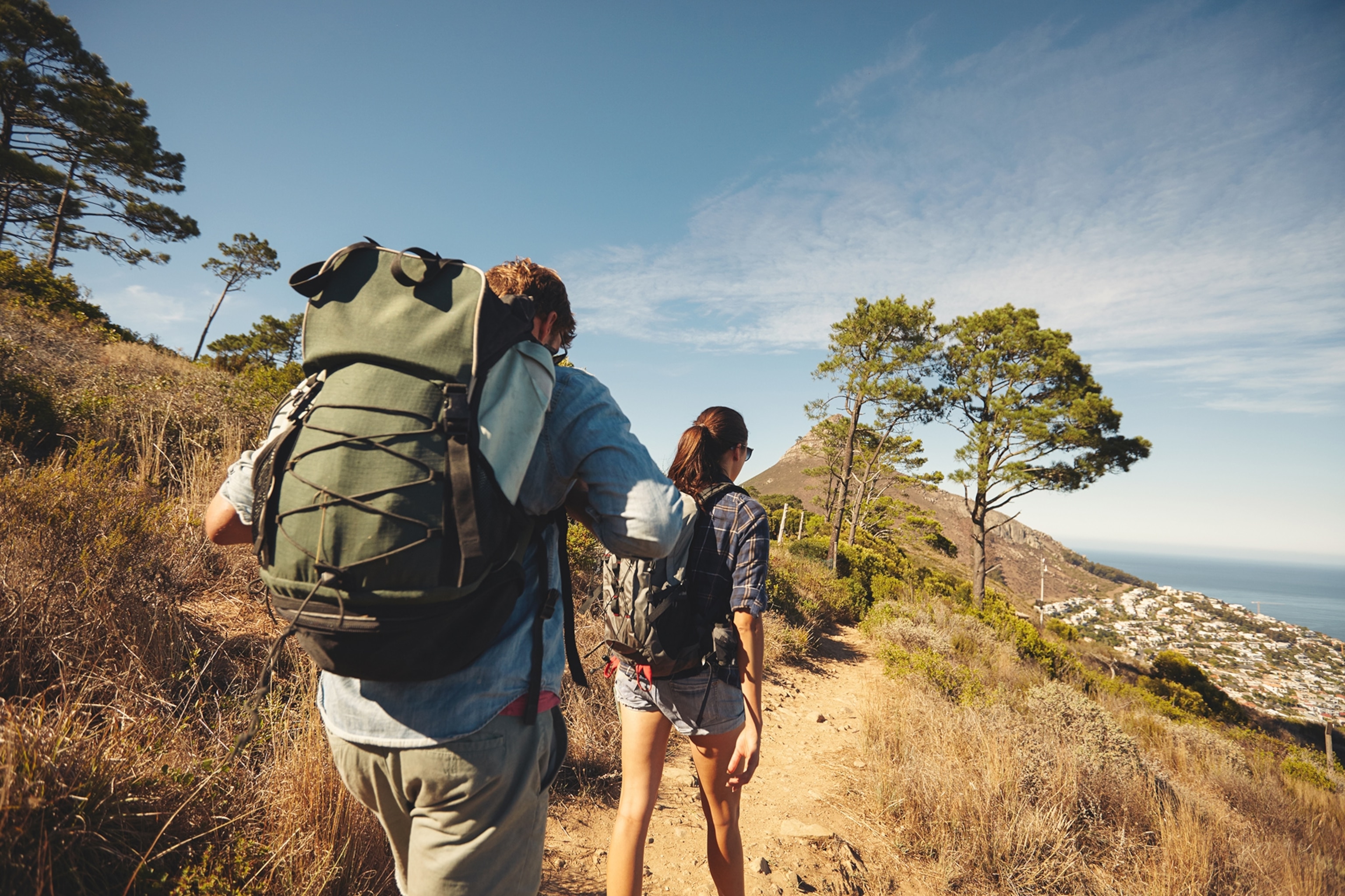 A man with a backpack and a woman with a backpack walking, on a sunny day outdoors.