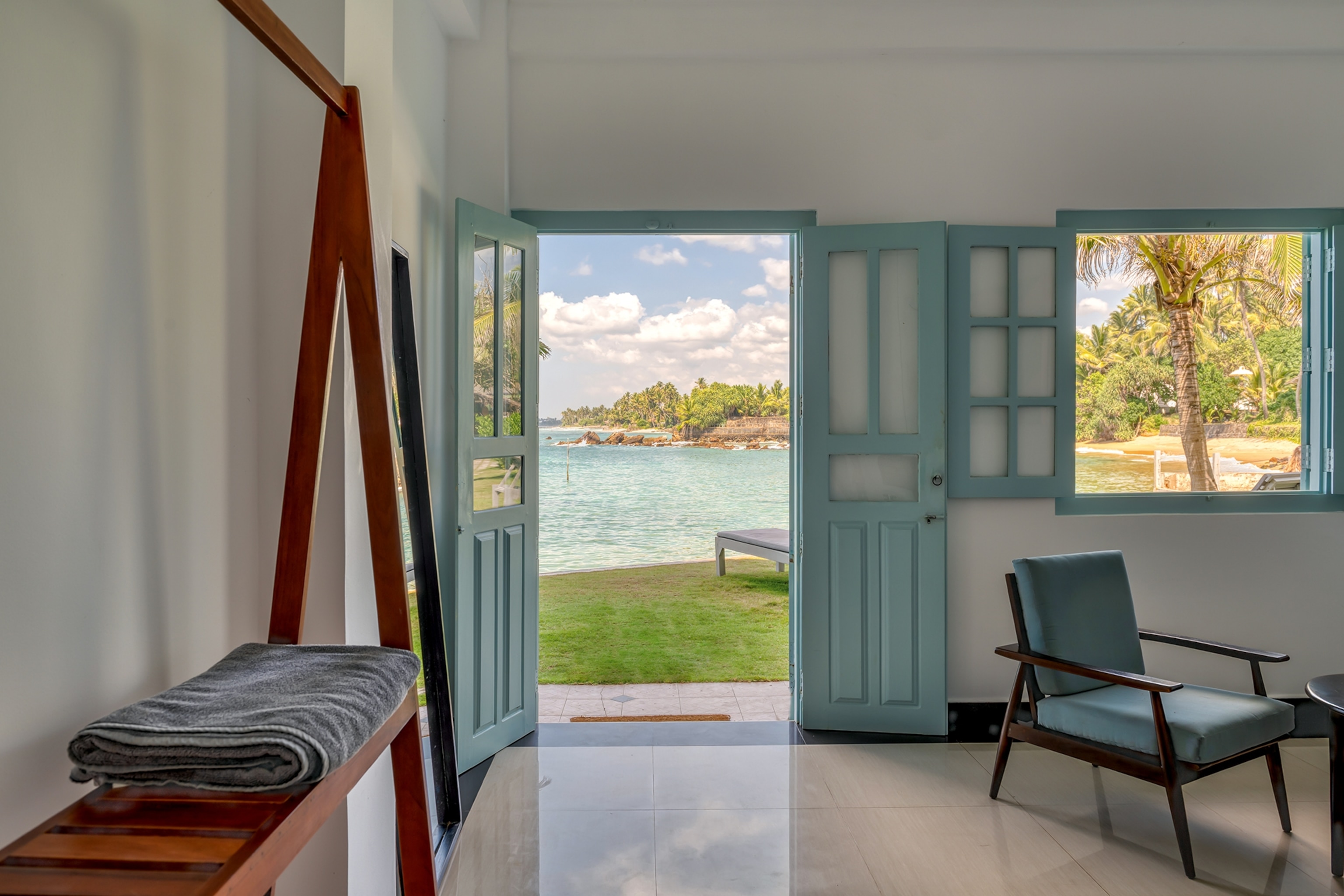 Looking out from a room through an open door to the sea and palm trees