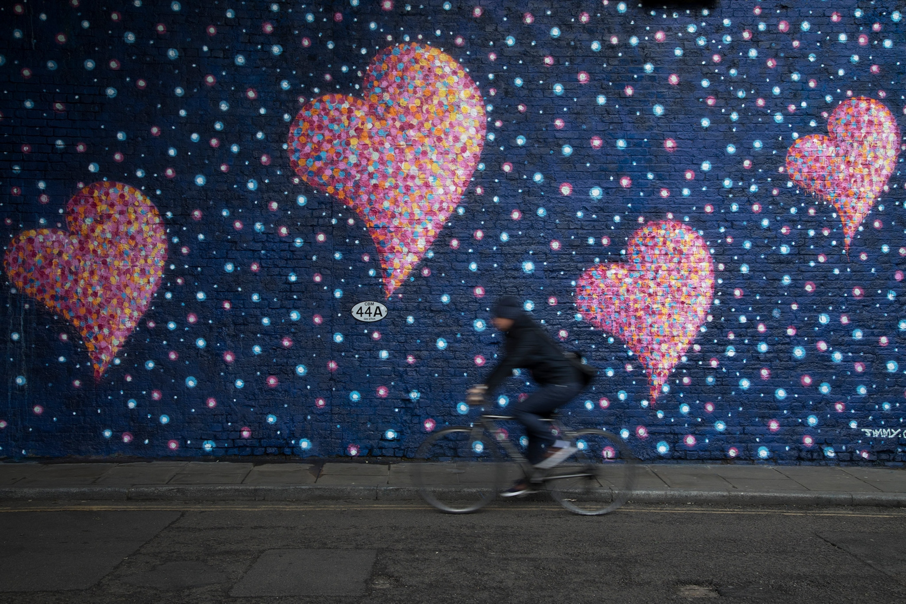 a person cycling past a heart mural at Borough Market in London, United Kingdom