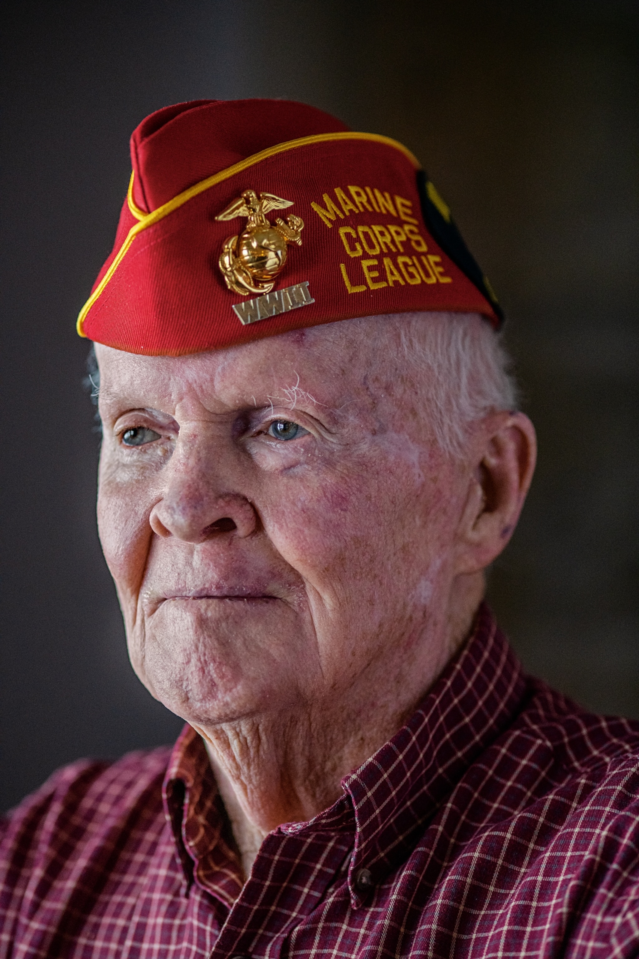 a man wearing a red plaid shirt and a red marine corps cap