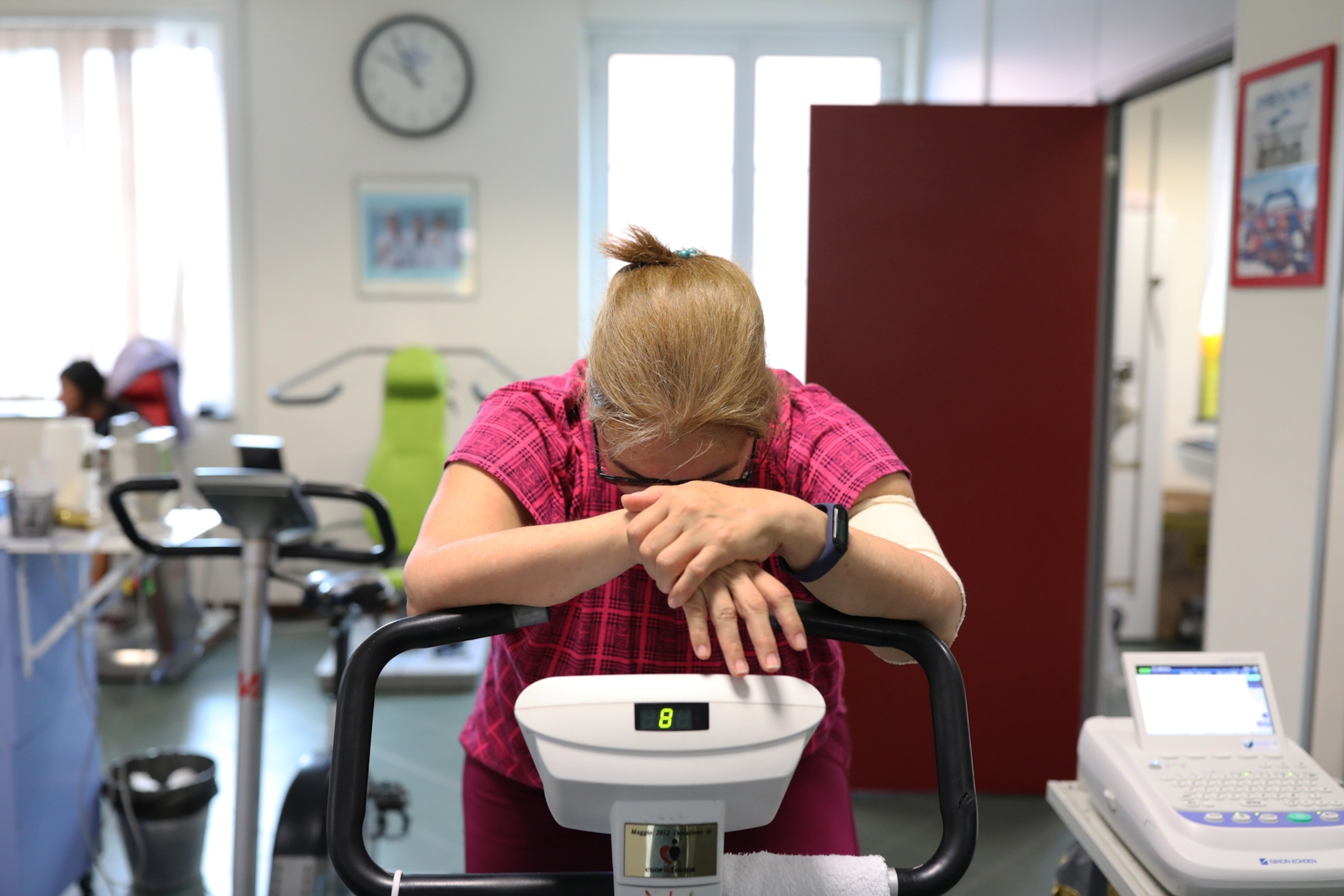 A patient suffering from chronic fatigue after being infected with COVID-19 takes a rest during rehabilitation exercises on a stationary bike.