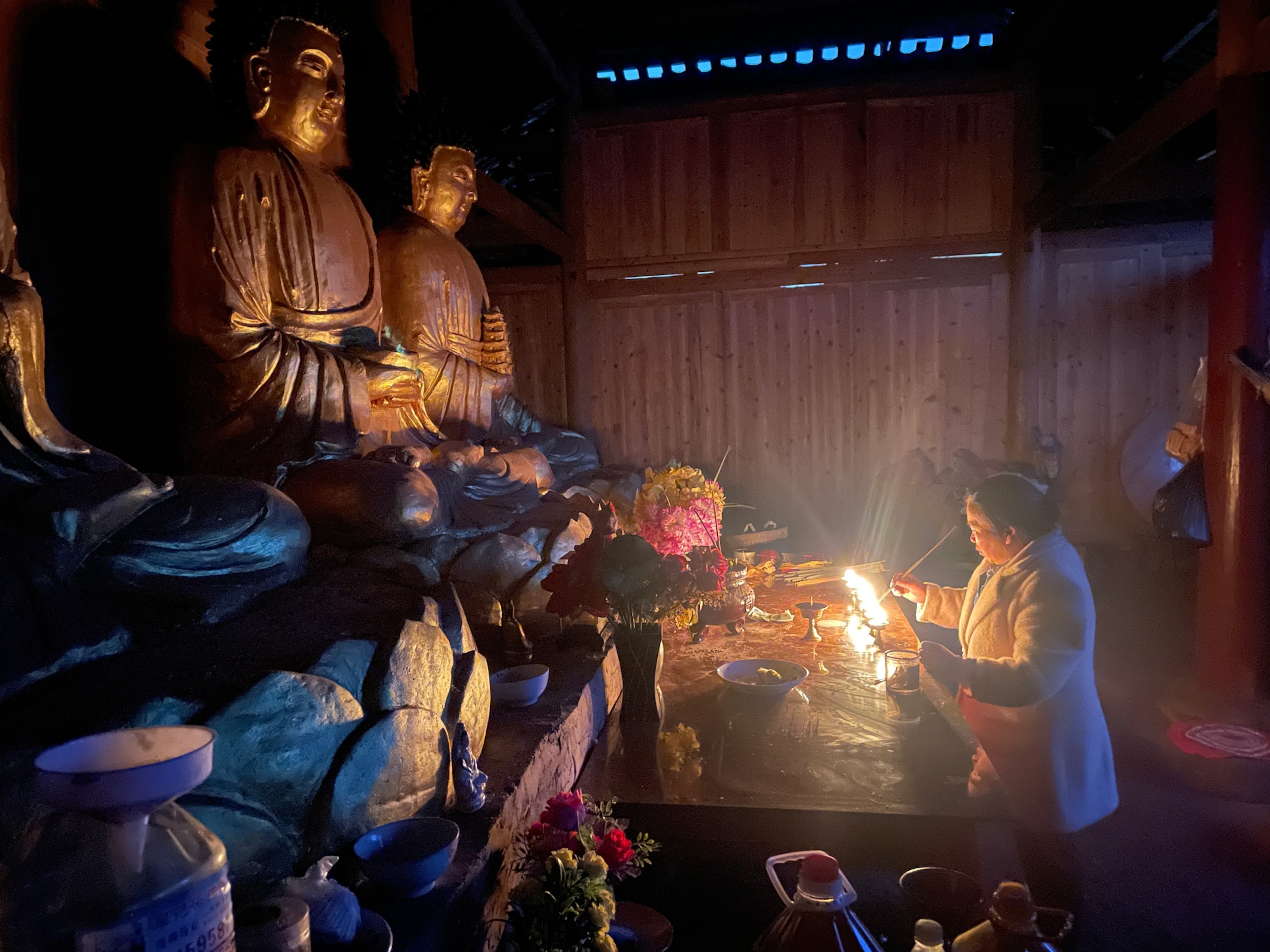 Photo of woman lighting candles in front of Buddha statues