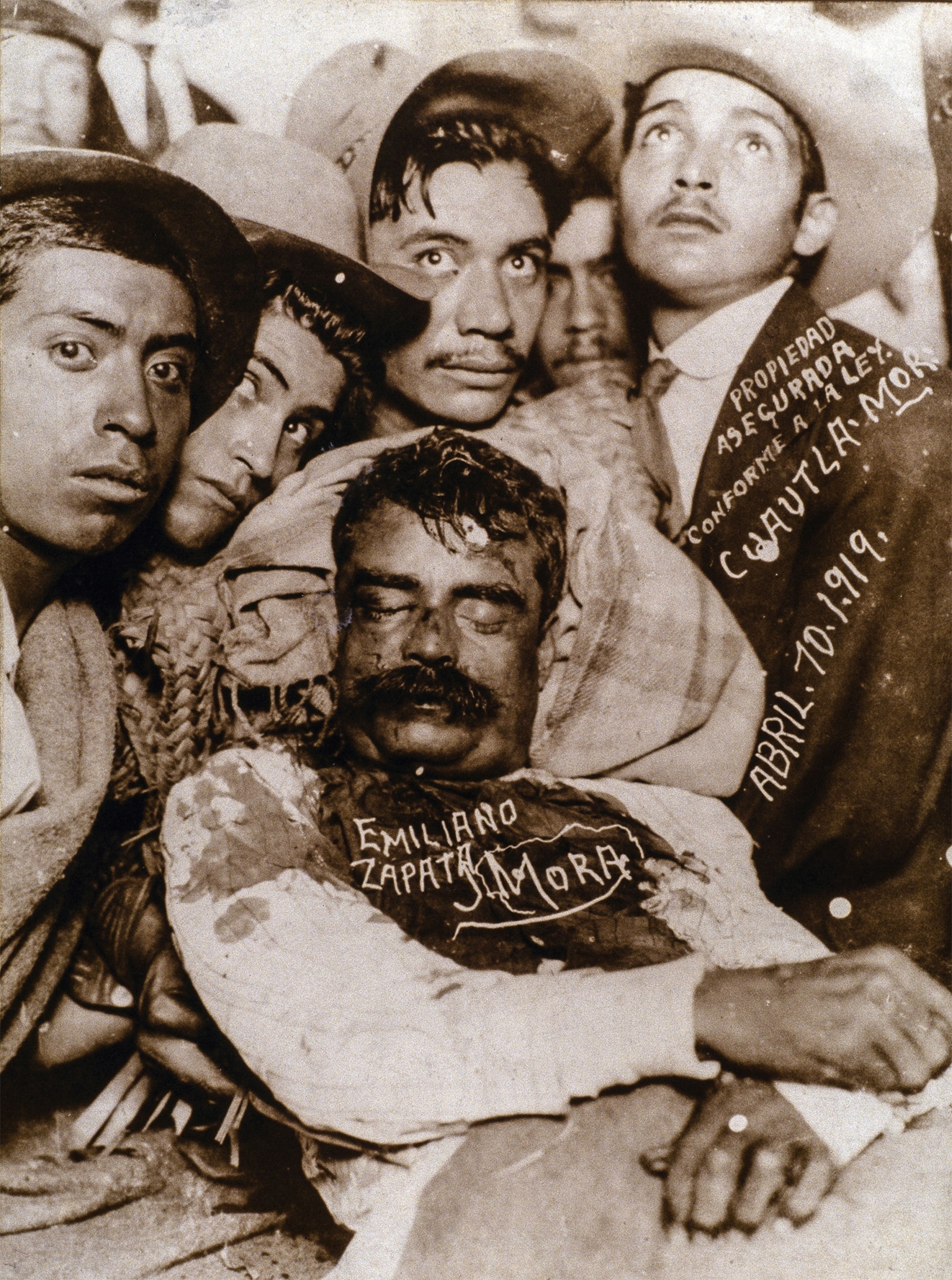 A photo of Zapata's corpse held up by other men, with white lettering on the photo stating his name, the photographer, and date