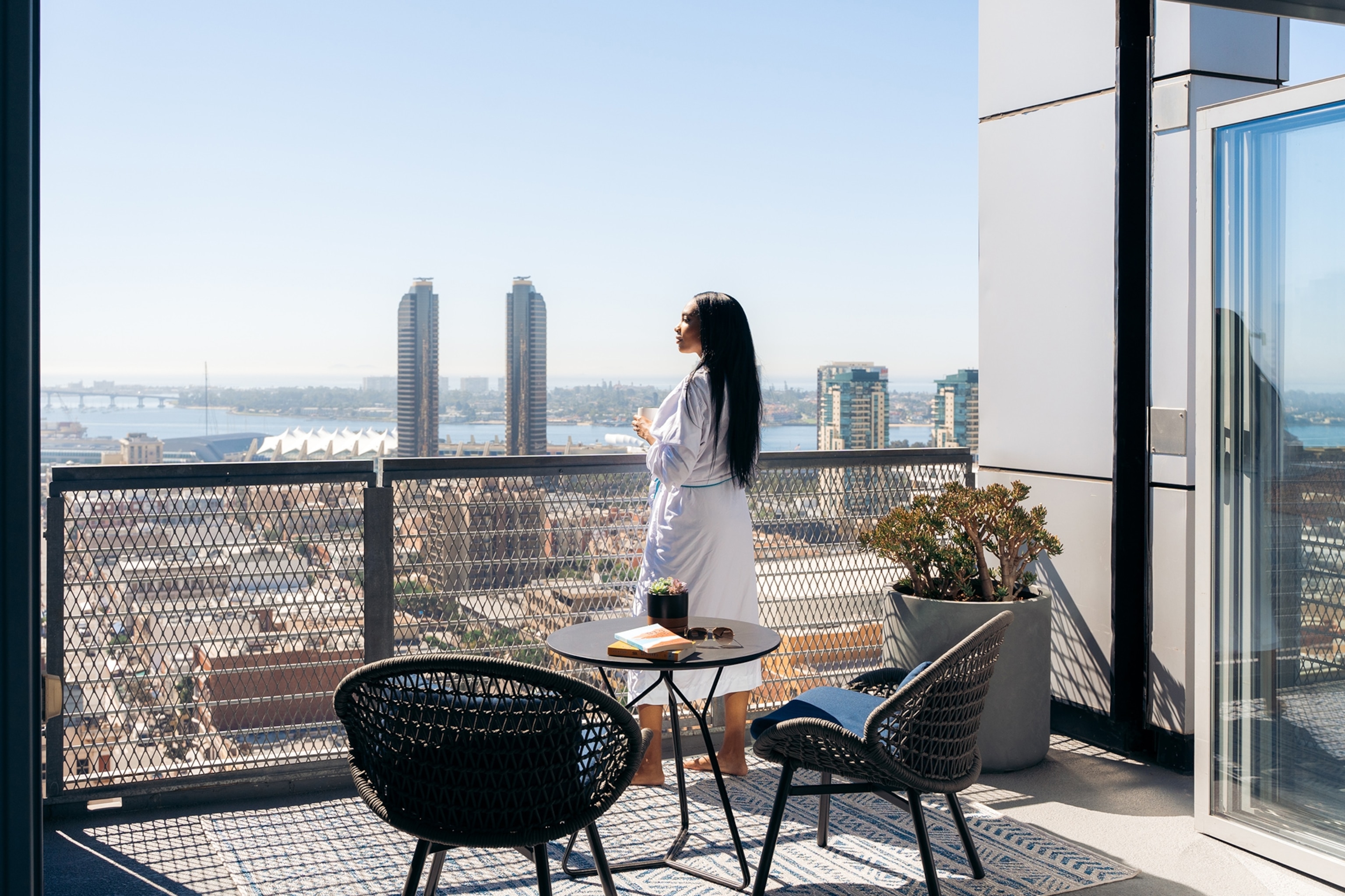 A person looks out at the San Diego skyline from the Penthouse balcony at the Kimpton Alma San Diego Hotel.