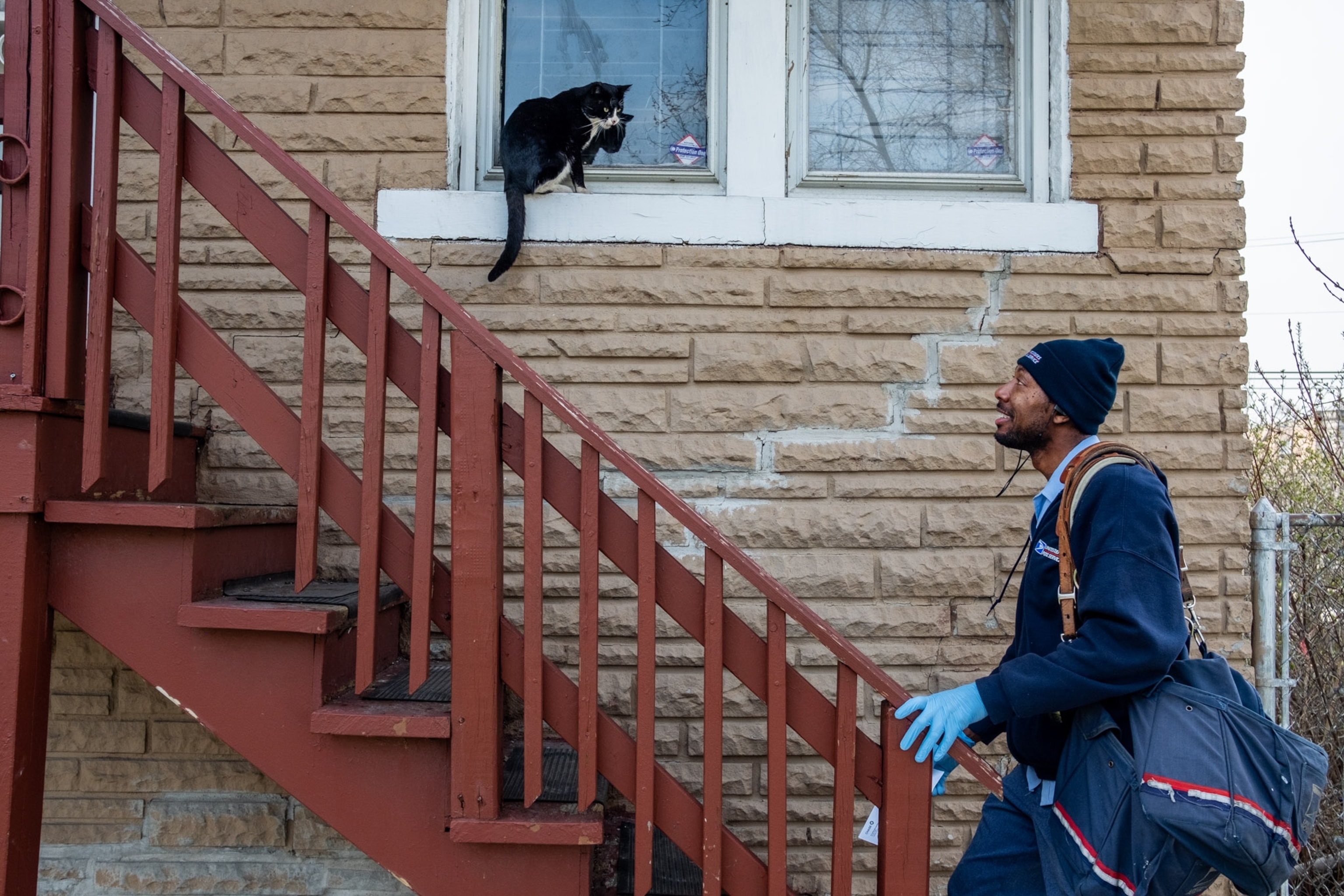 a post office worker walking up a set of outdoor stairs