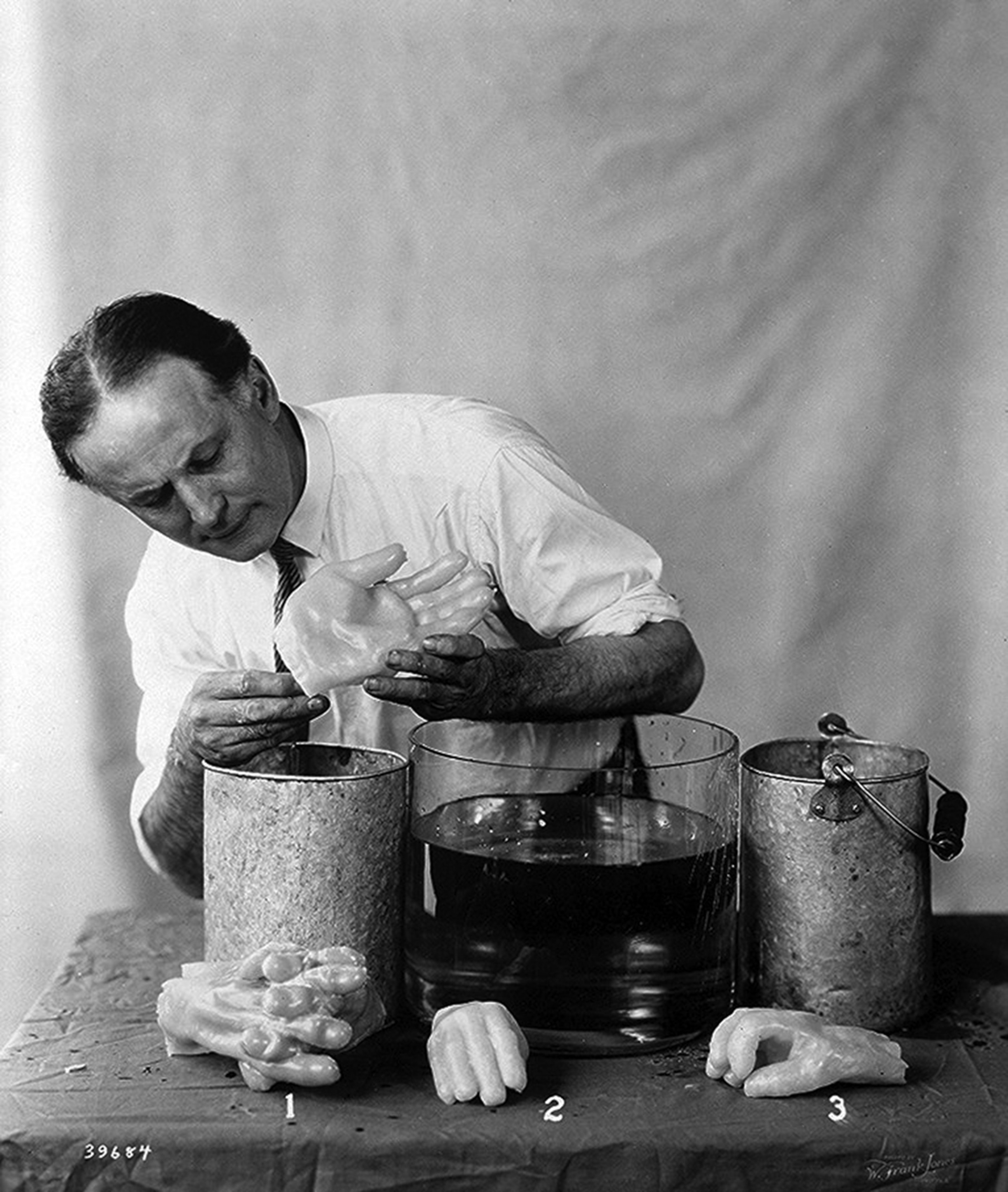 Houdini holds a plaster mold of a hand as he demonstrates the process behind "finger-printing a spirit."