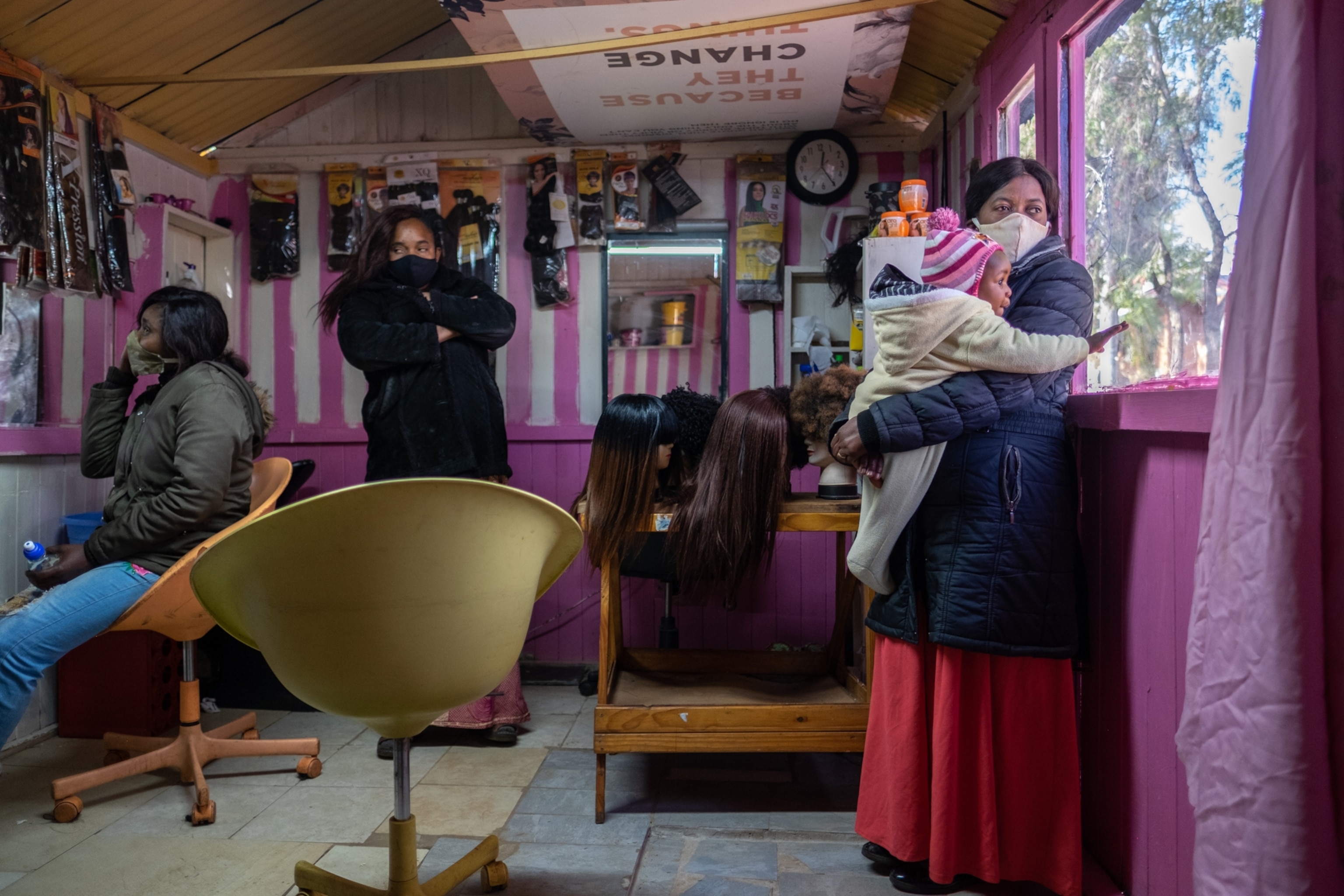 a person holding a child near a window within a hair salon
